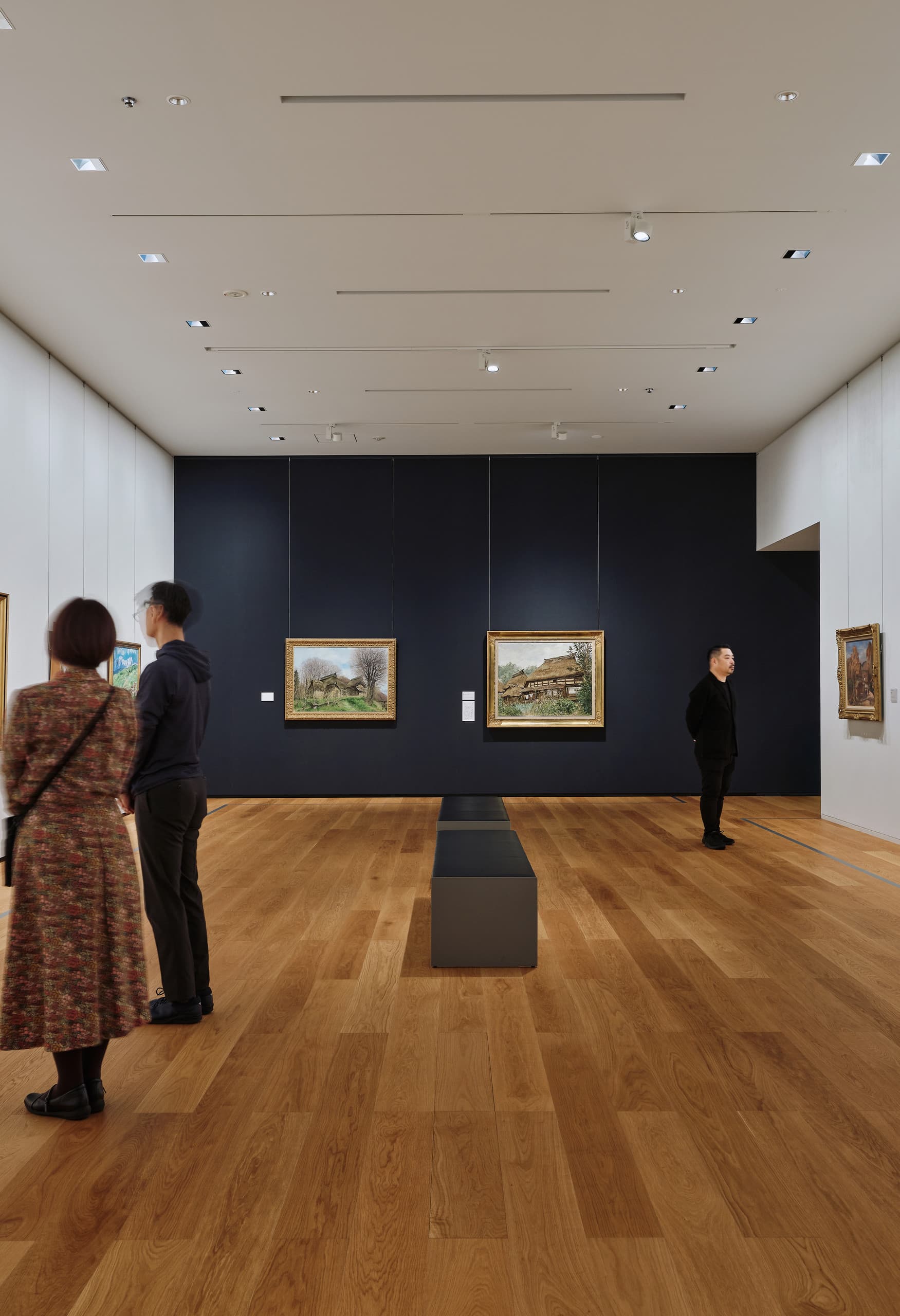 Ausstellungsraum im Museum mit Gemälden auf weißen und schwazrer Wand.