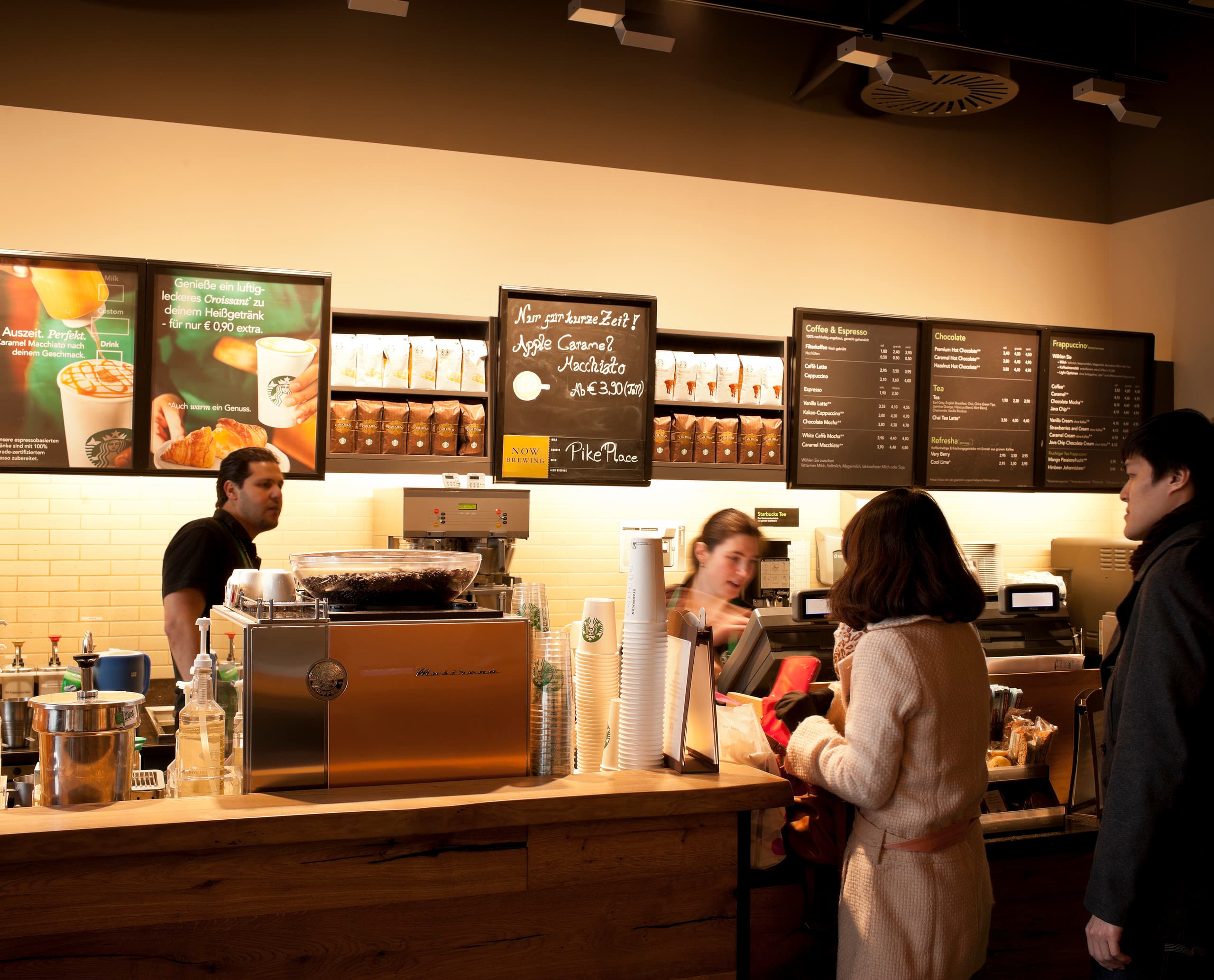 Beleuchteter Starbucks Coffee House Tresen in Koblenz mit Kunden und Mitarbeitern.
