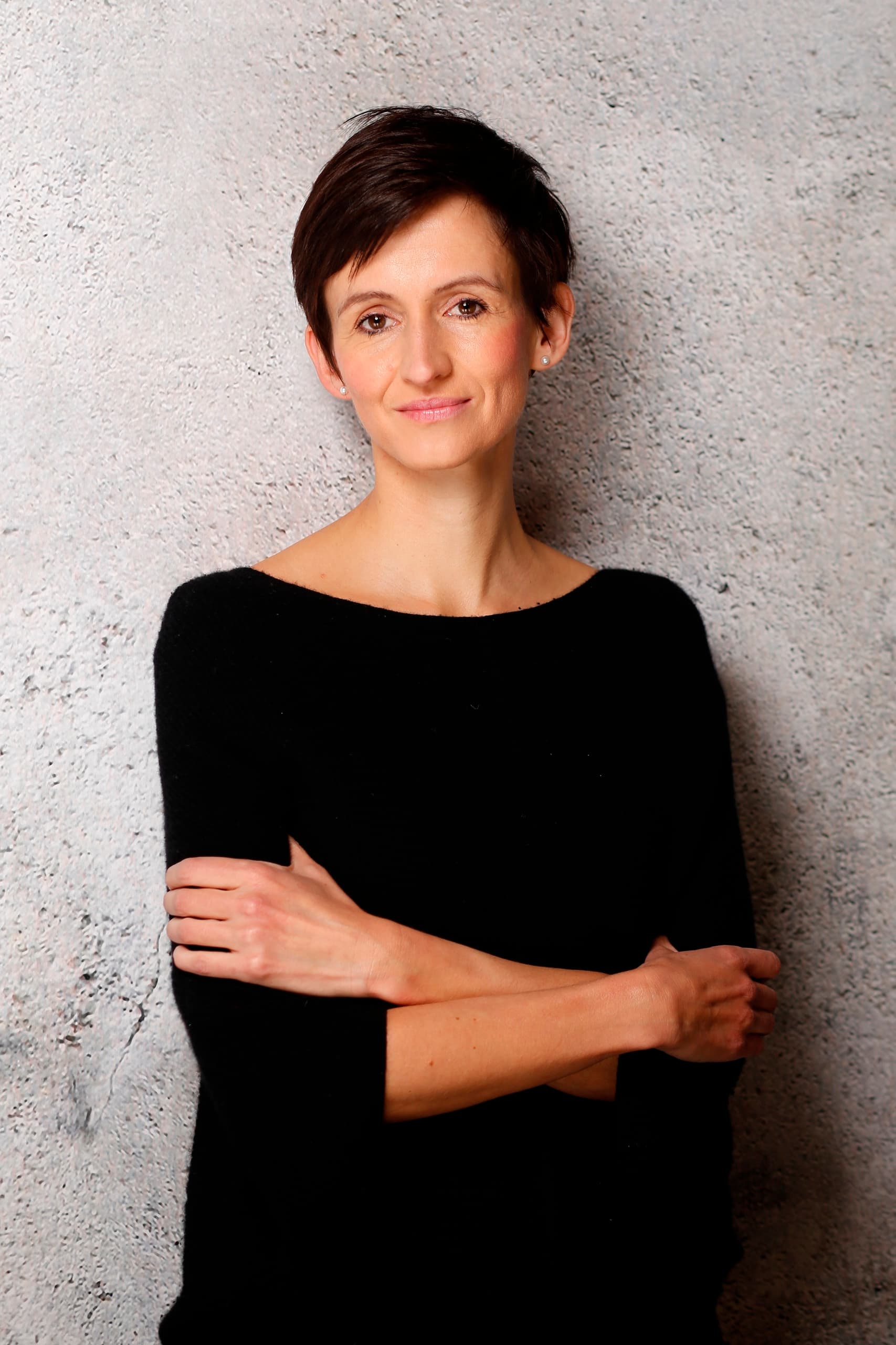 Wiebke Lang, Journalistin für Design, Architektur und Branding, im Porträt vor einer grauen Wand.