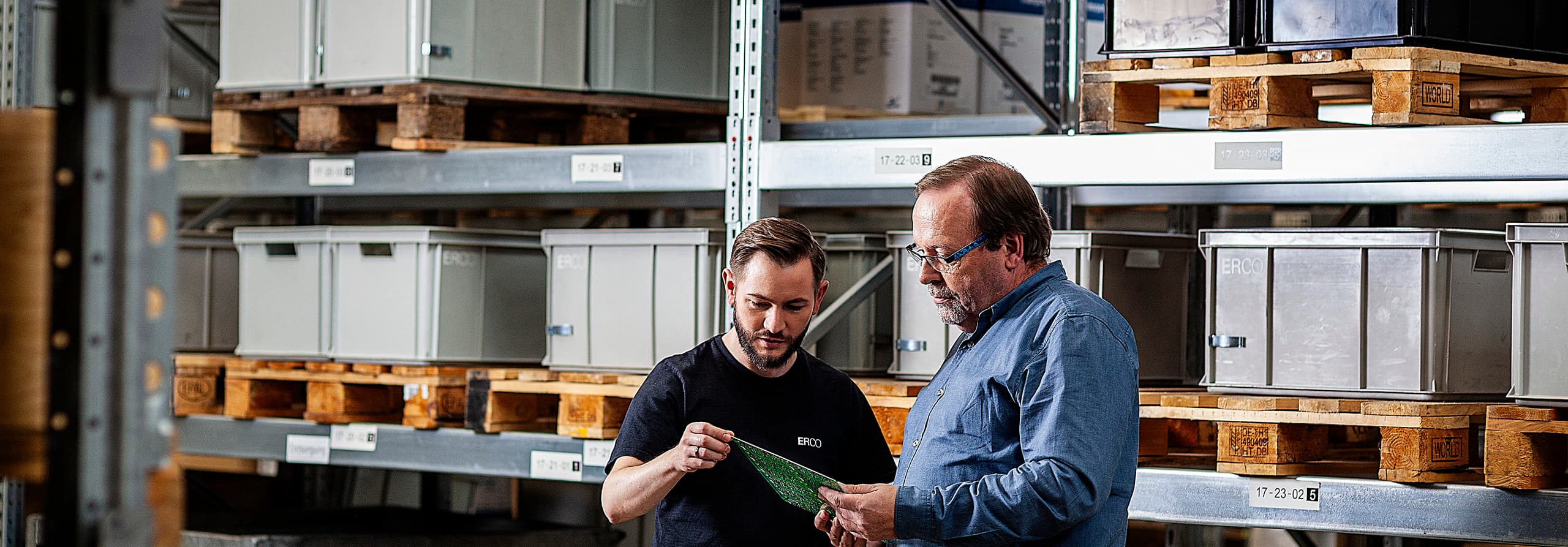 ERCO-Mitarbeiter prüfen Bauteil im Lager, Qualitätssicherung für Architekturbelichtung.