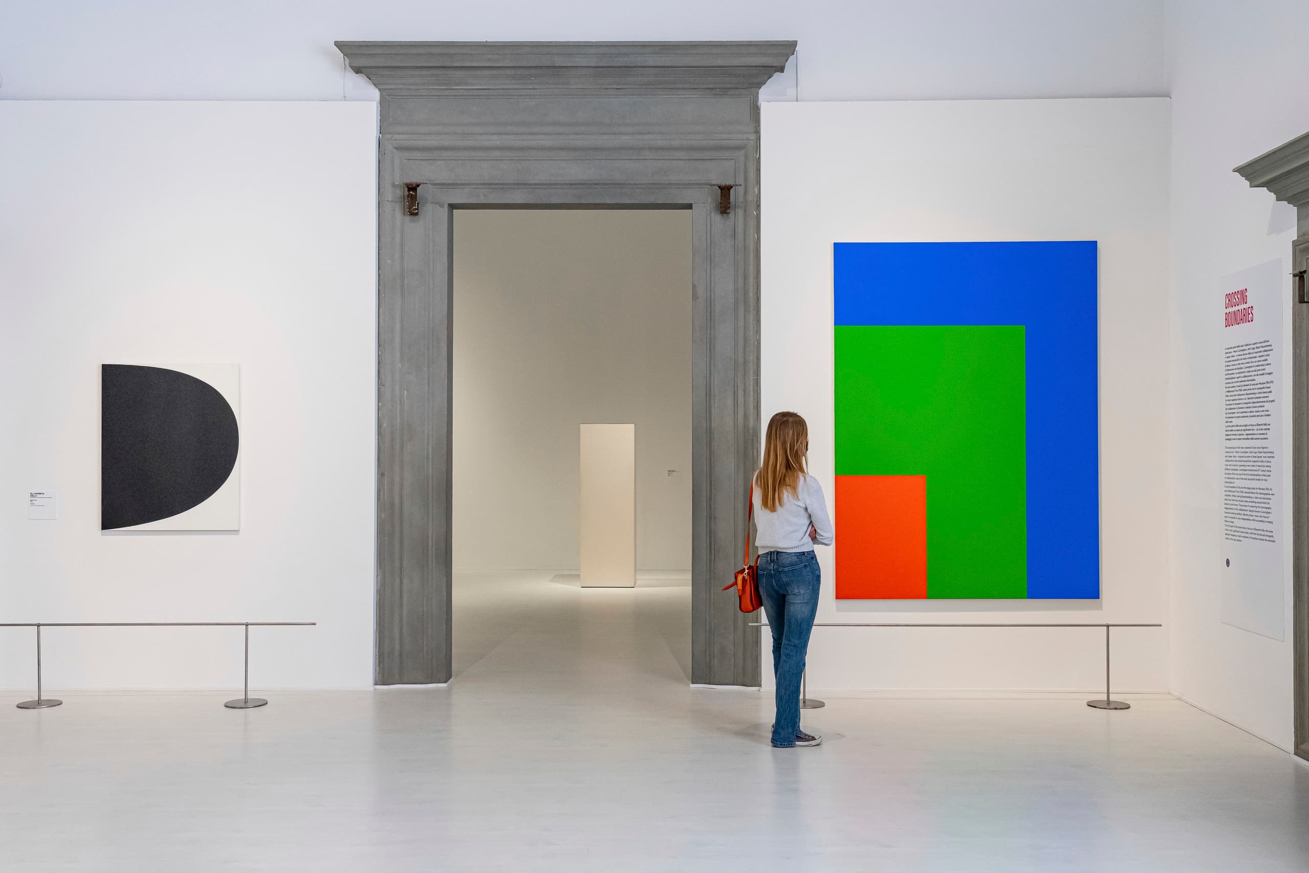 Frau betrachtet Gemälde mit Farbkontrasten in einer Kunstgalerie. Lichtdesign.
