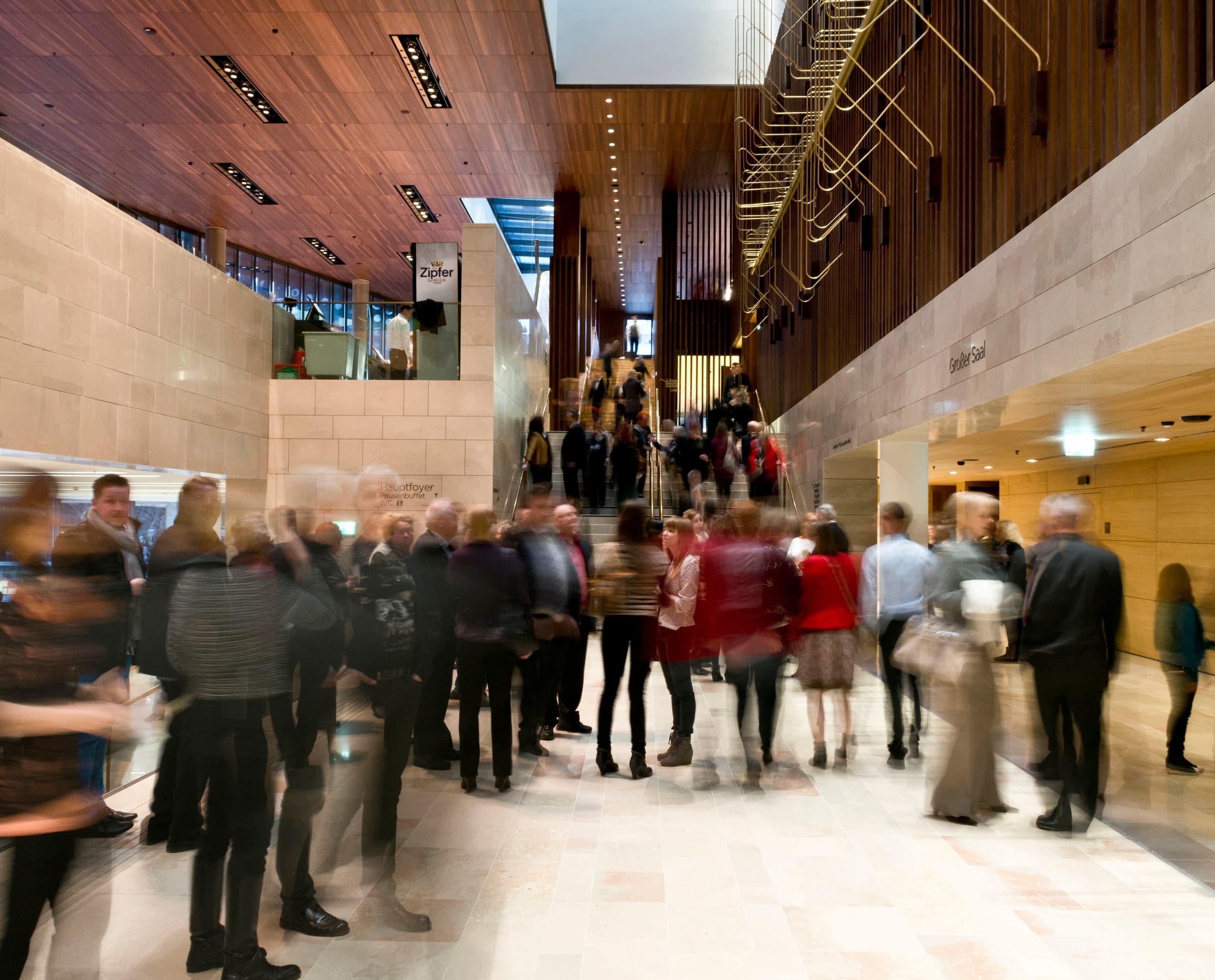 Foyer des Linzer Musiktheaters mit ERCO Beleuchtung und Besuchern.