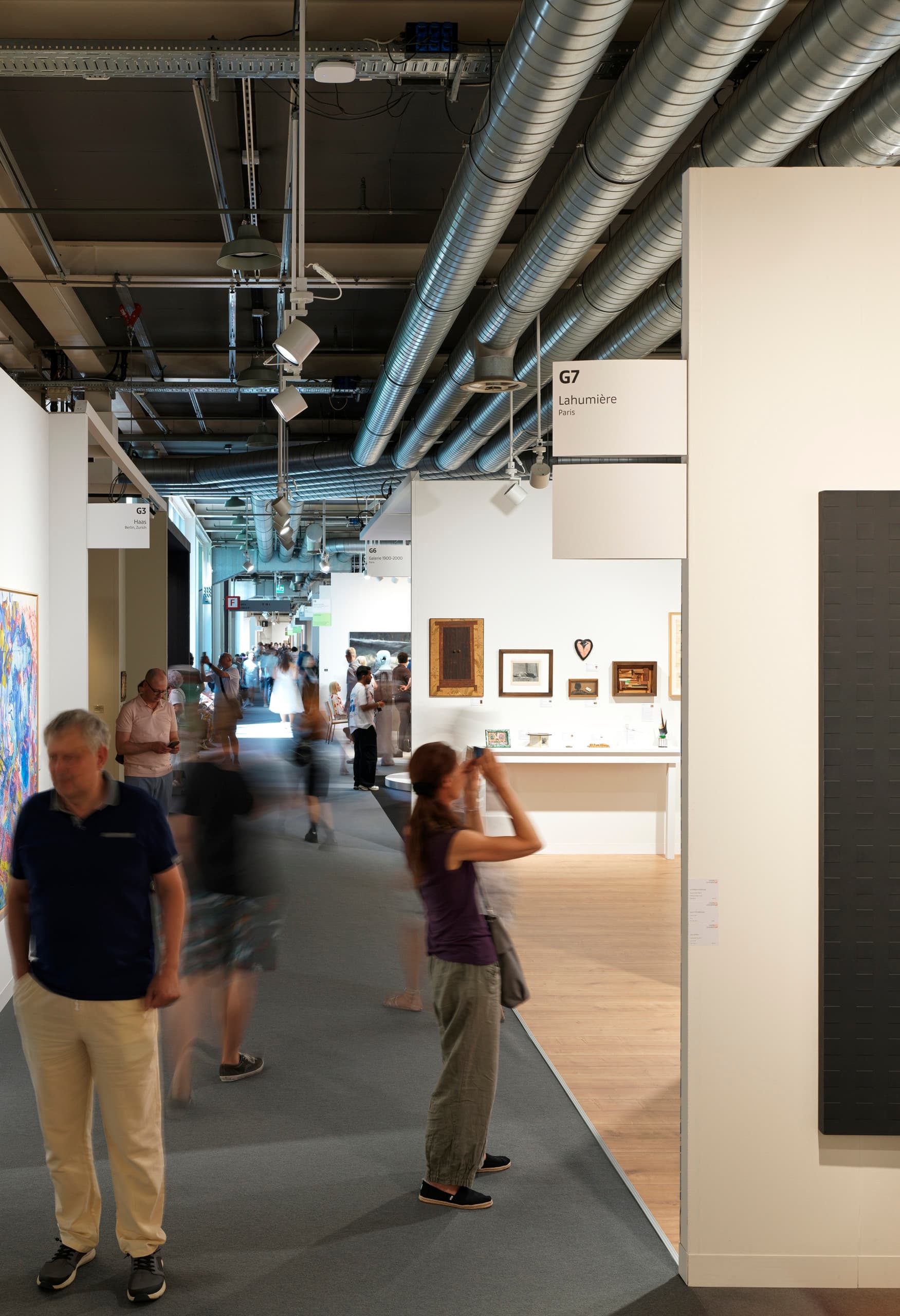 Gang mit Menschen auf der Messe Art Basel, schwarzes rechteckiges Bild im Fokus.