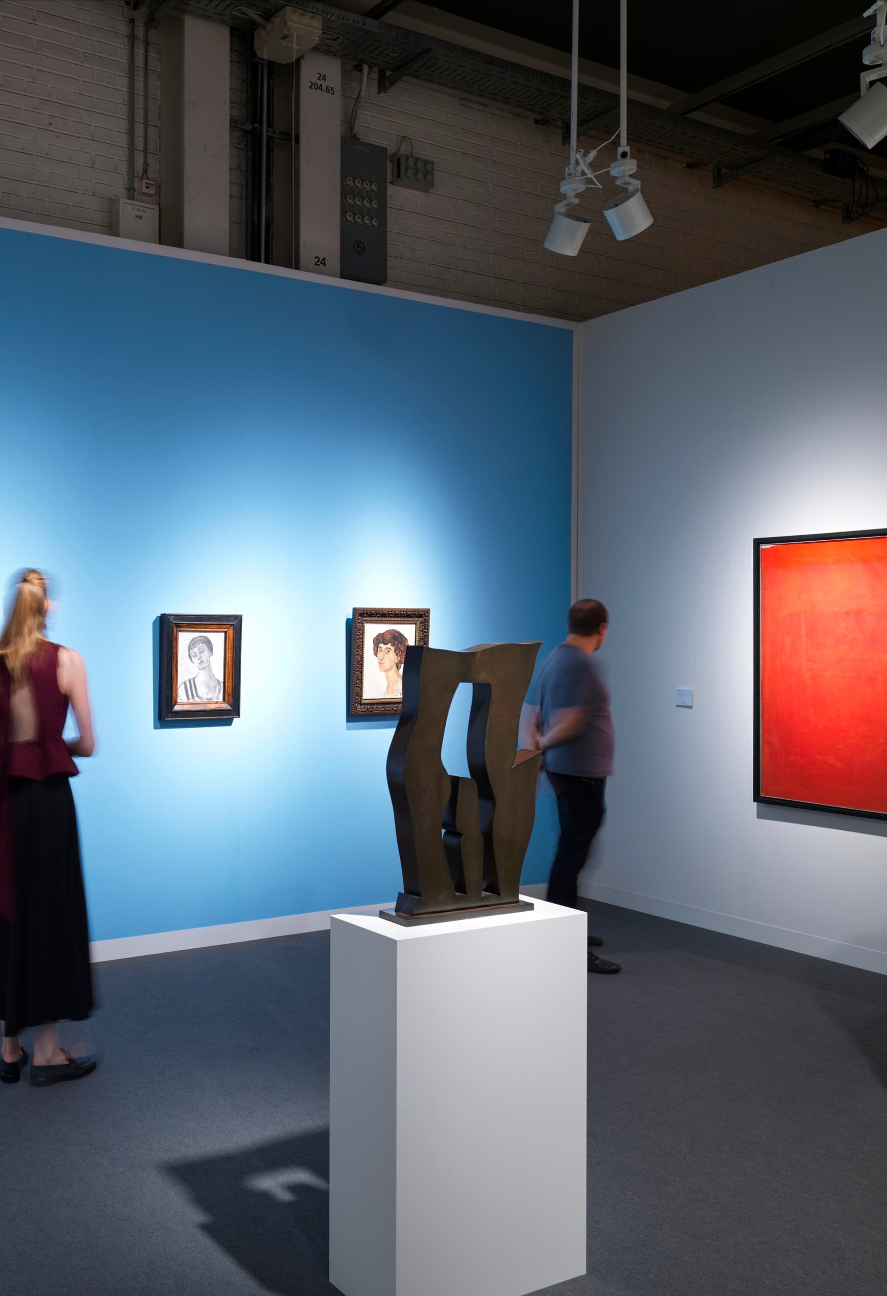 Messestand auf der Art Basel mit Bildern auf blauer Wand.