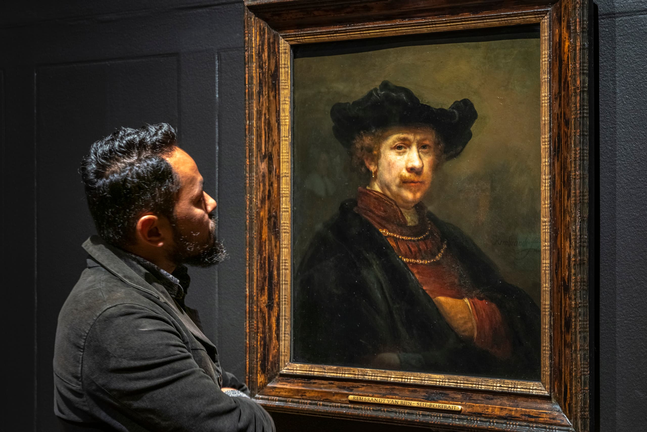 Ein Mann betrachtet ein Gemälde von Rembrandt, wobei die Lichtgestaltung die Wahrnehmung beeinflusst.