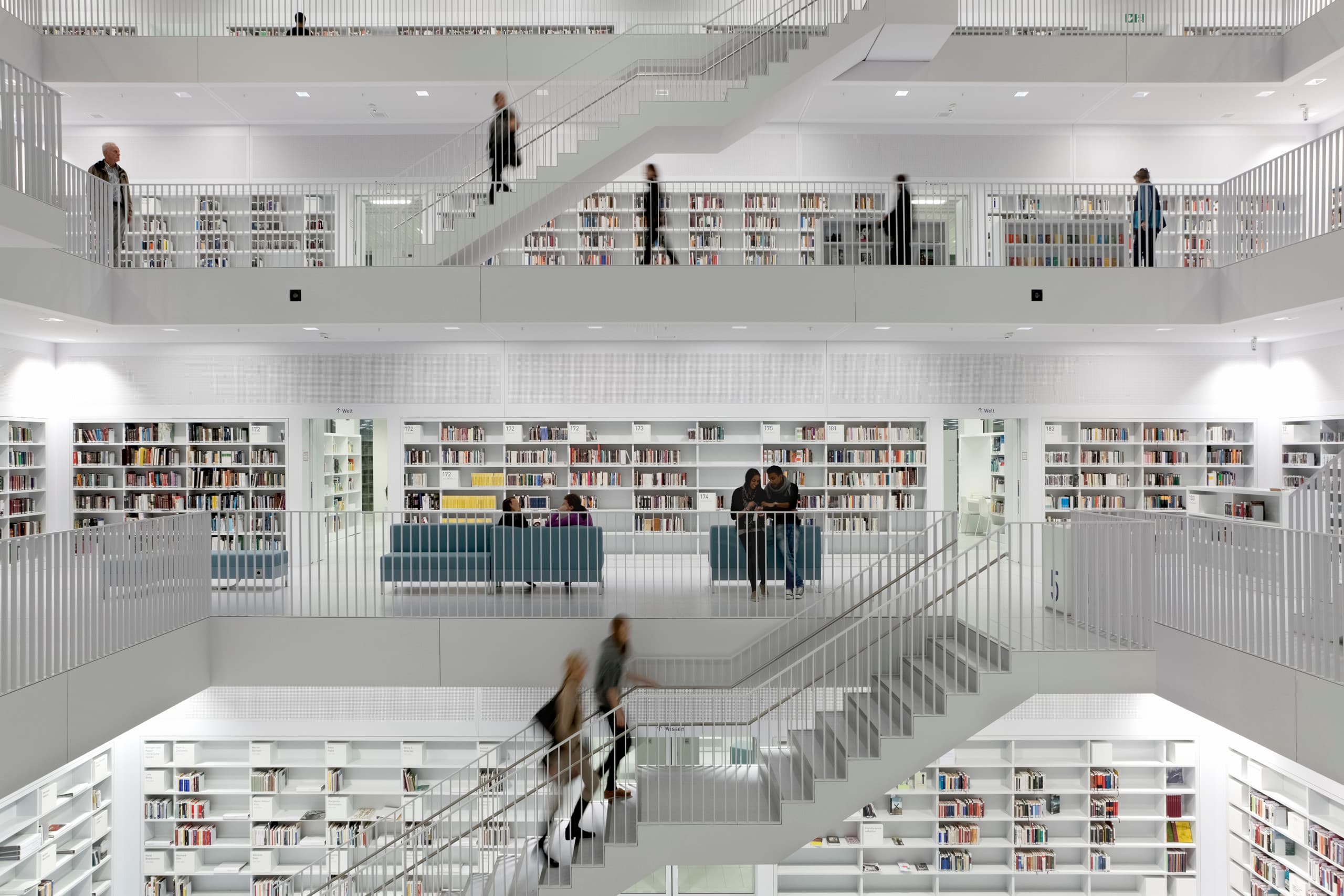 Innenansicht einer Bibliothek mit mehreren Etagen, Treppen und Regalen voller Bücher, beleuchtet mit ERCO Licht.