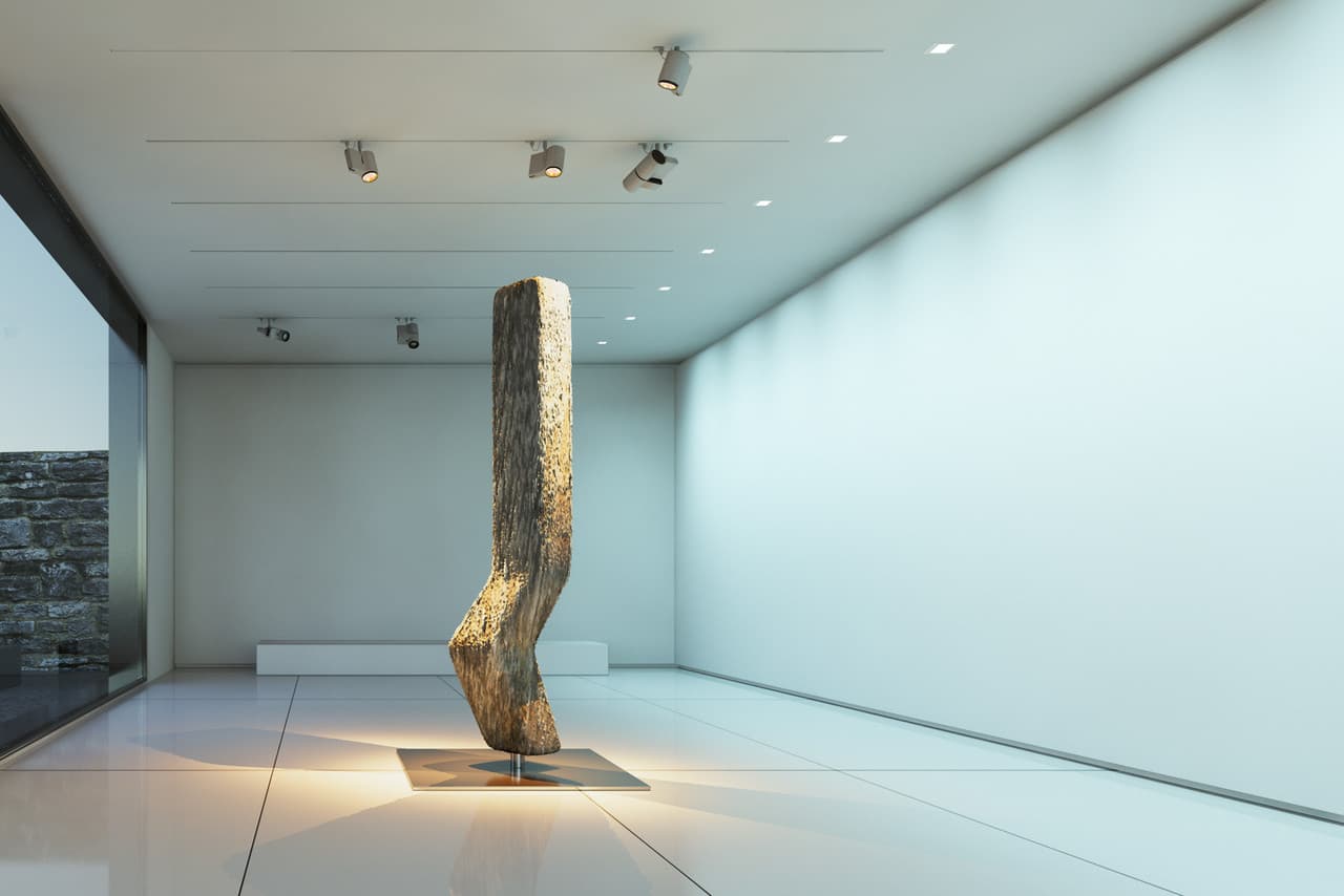 Beleuchtete Holzskulptur in einem Ausstellungsraum, akzentuiert durch gerichtetes Licht von ERCO Strahlern.