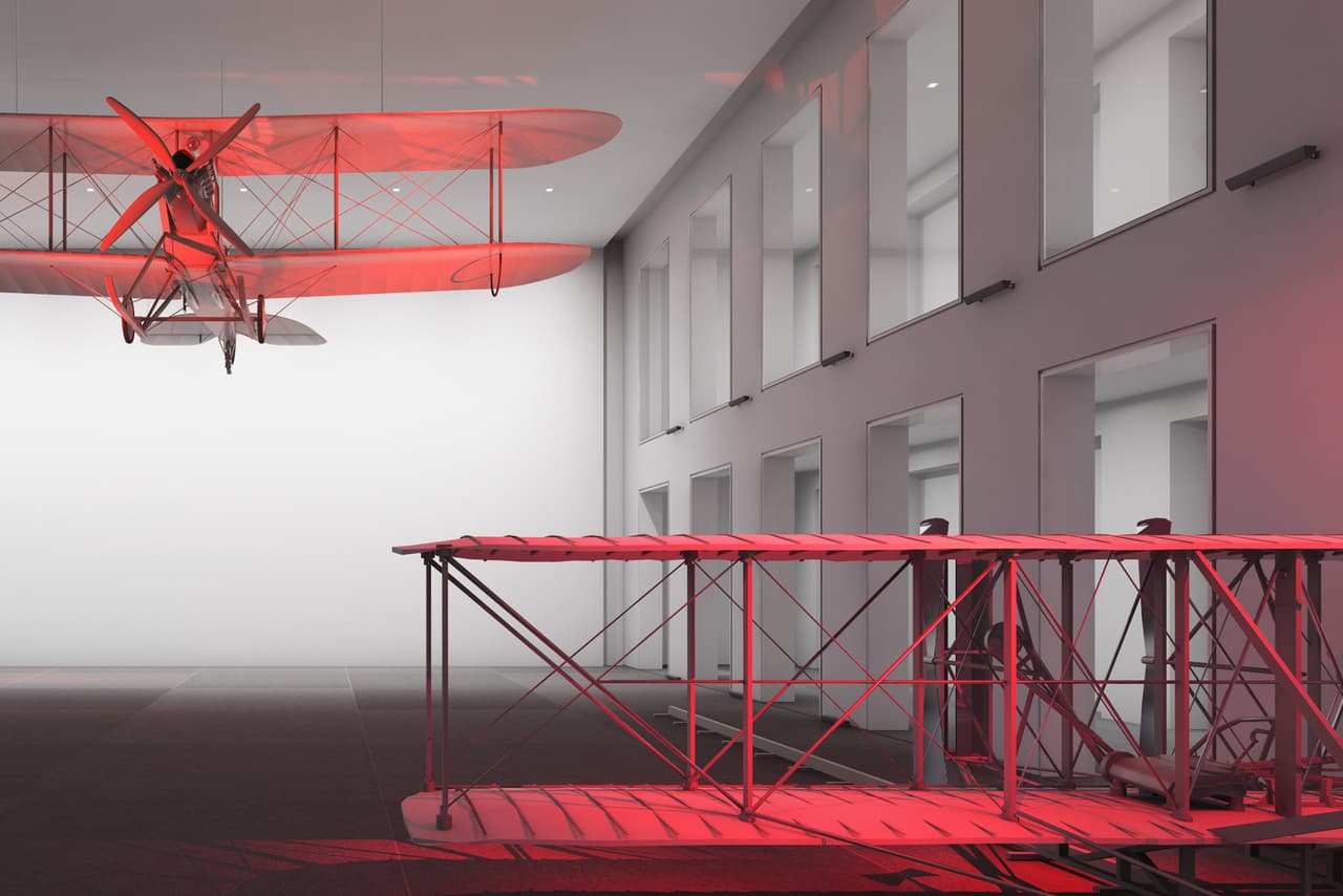 Rotes Licht akzentuiert Flugzeugmodelle, die räumliche Differenzierung und intensive Farbstimmung erzeugen.