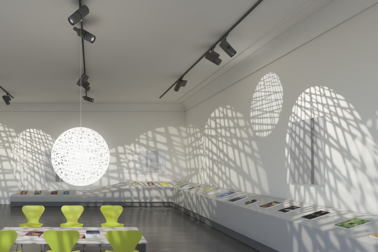 ERCO Lichtlösung mit neutraler Beleuchtung und Akzenten durch Strahler und Pendelleuchte in einem Ausstellungsraum.