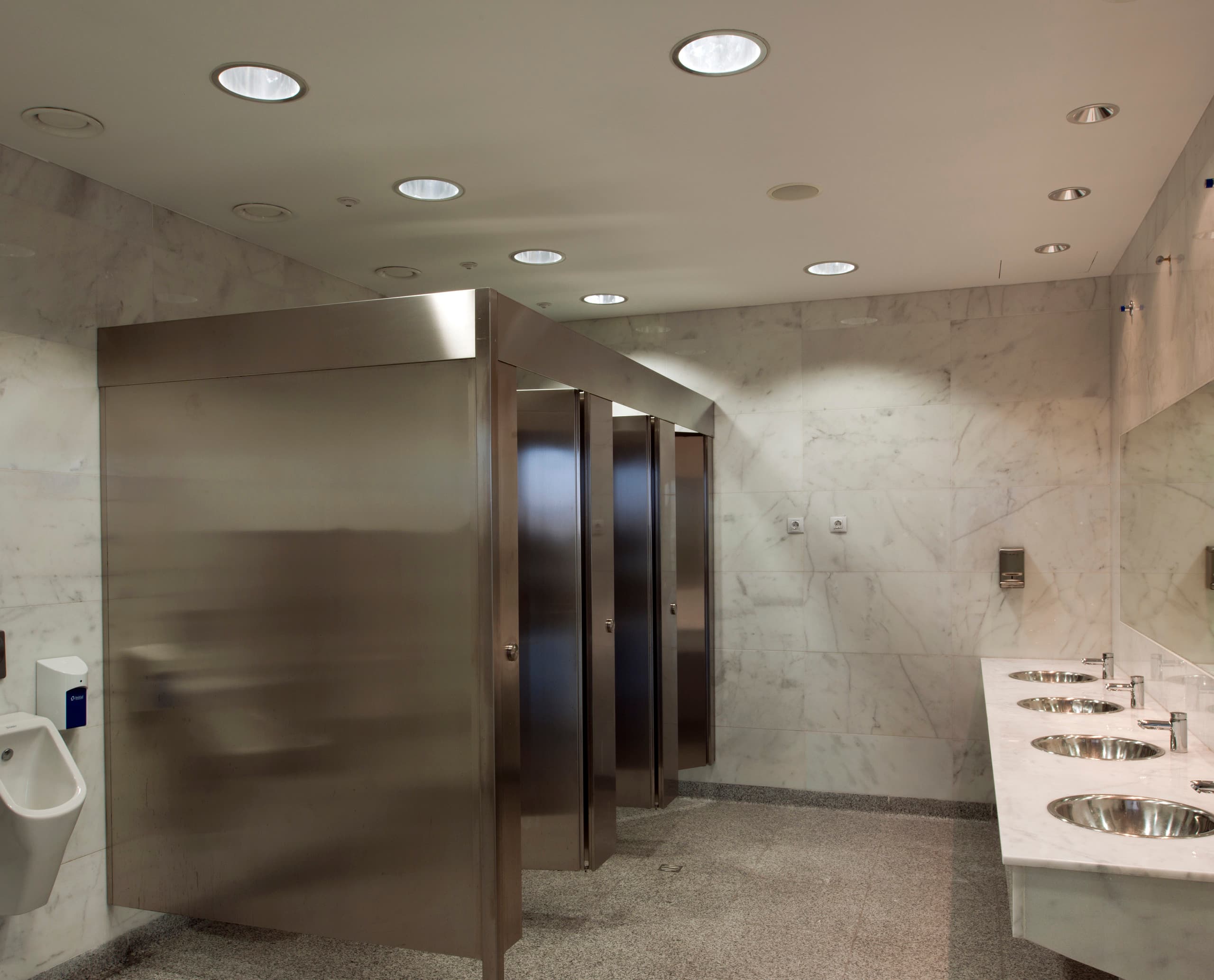 Moderne Toiletten im Terminal 3 des Flughafens Malaga mit ERCO Downlights für effiziente Beleuchtung.