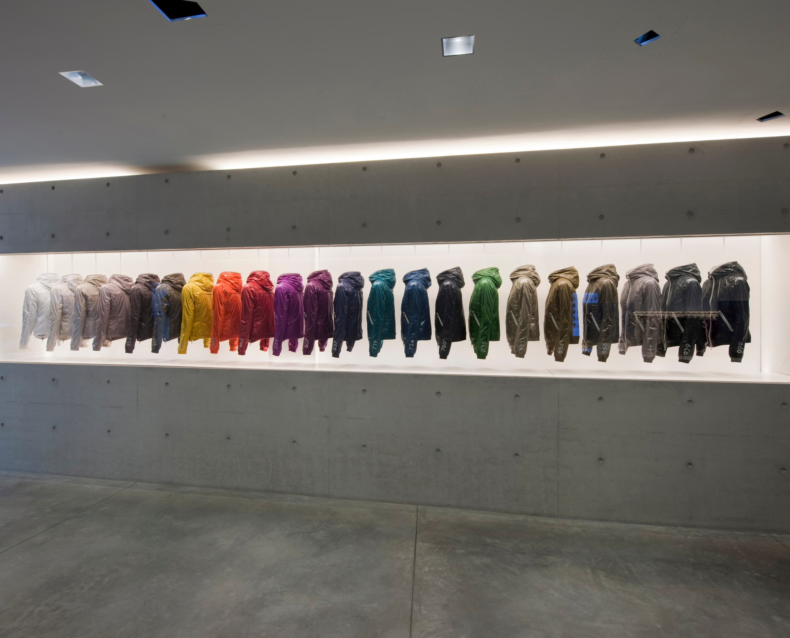 Duvetica Daunenjacken in einem minimalistischen Showroom, beleuchtet mit ERCO LED-Leuchten.