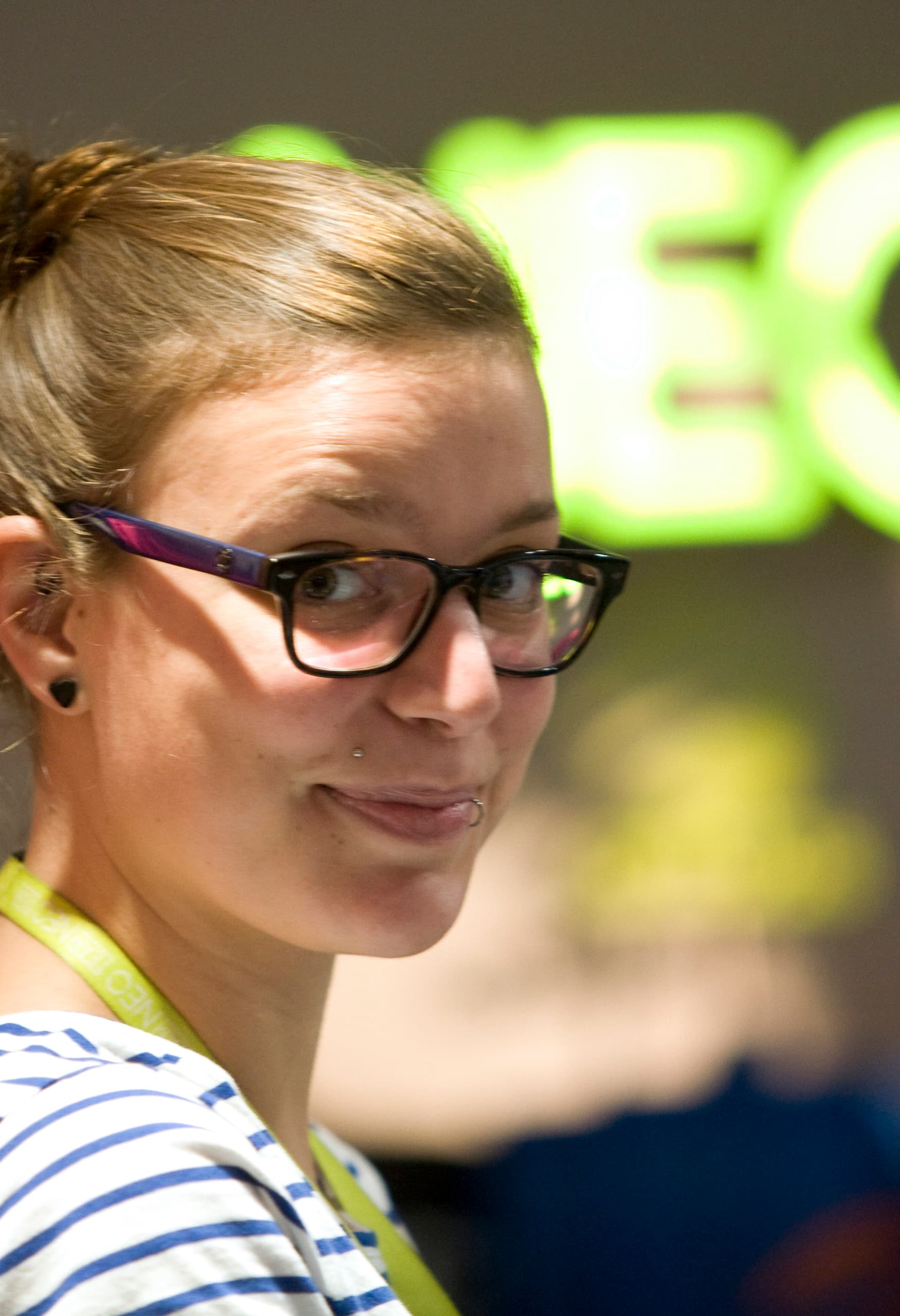 Frau vor dem beleuchteten Adidas NEO Logo, das die dynamische LED-Beleuchtung im Kölner Shop hervorhebt.