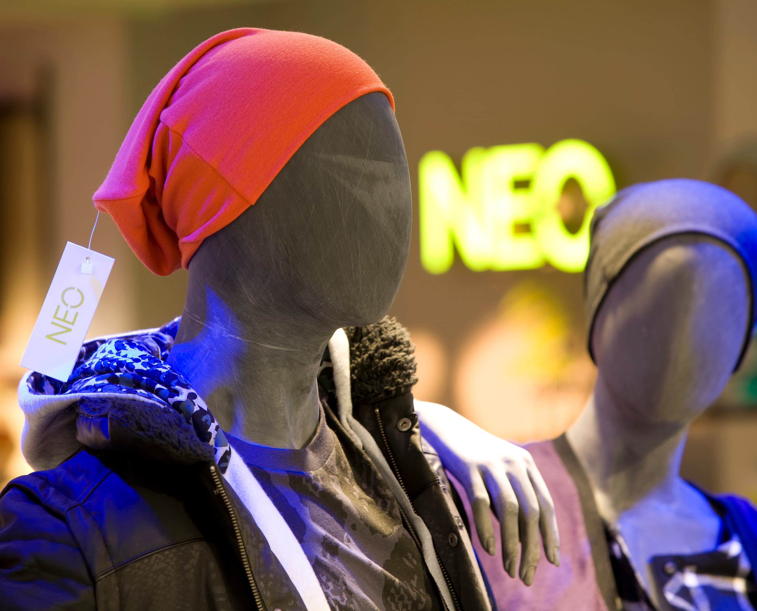 Adidas NEO Store: Schaufensterpuppe mit roter Mütze und Jacke unter LED-Beleuchtung.