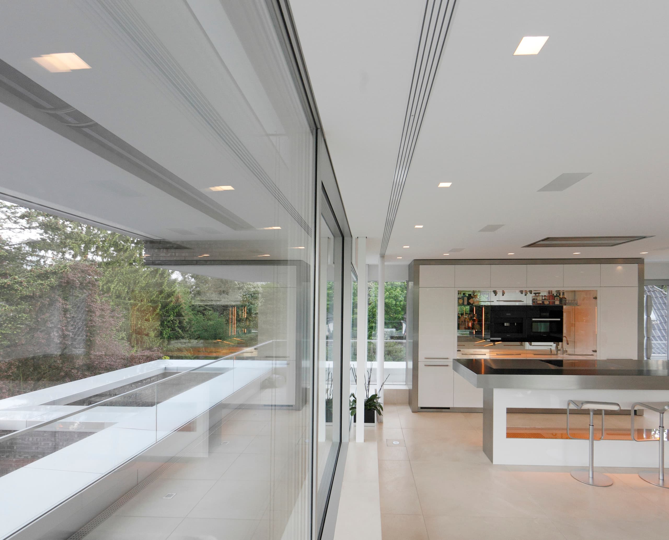 Moderne Villa Linari Küche mit ERCO LED-Beleuchtung und Blick ins Grüne.