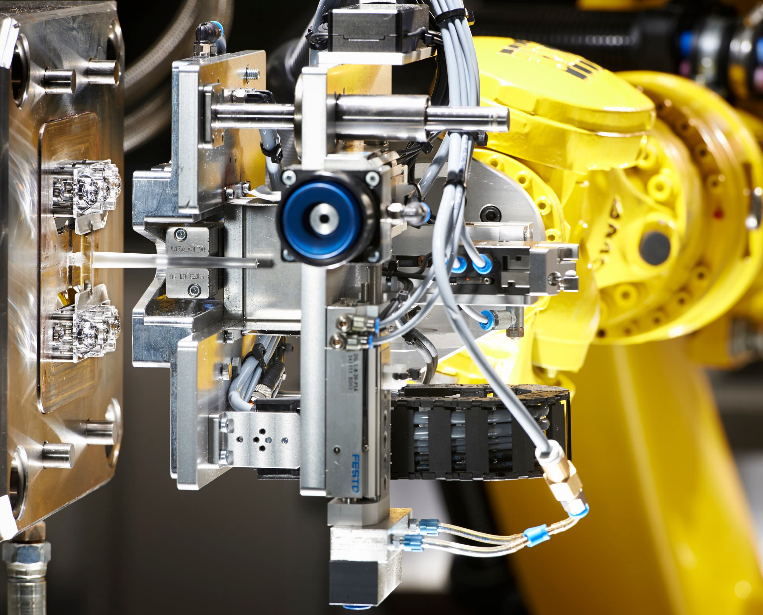 Automatisierte Fertigungszelle für ERCO LED-Linsen mit Industrieroboter in Aktion.