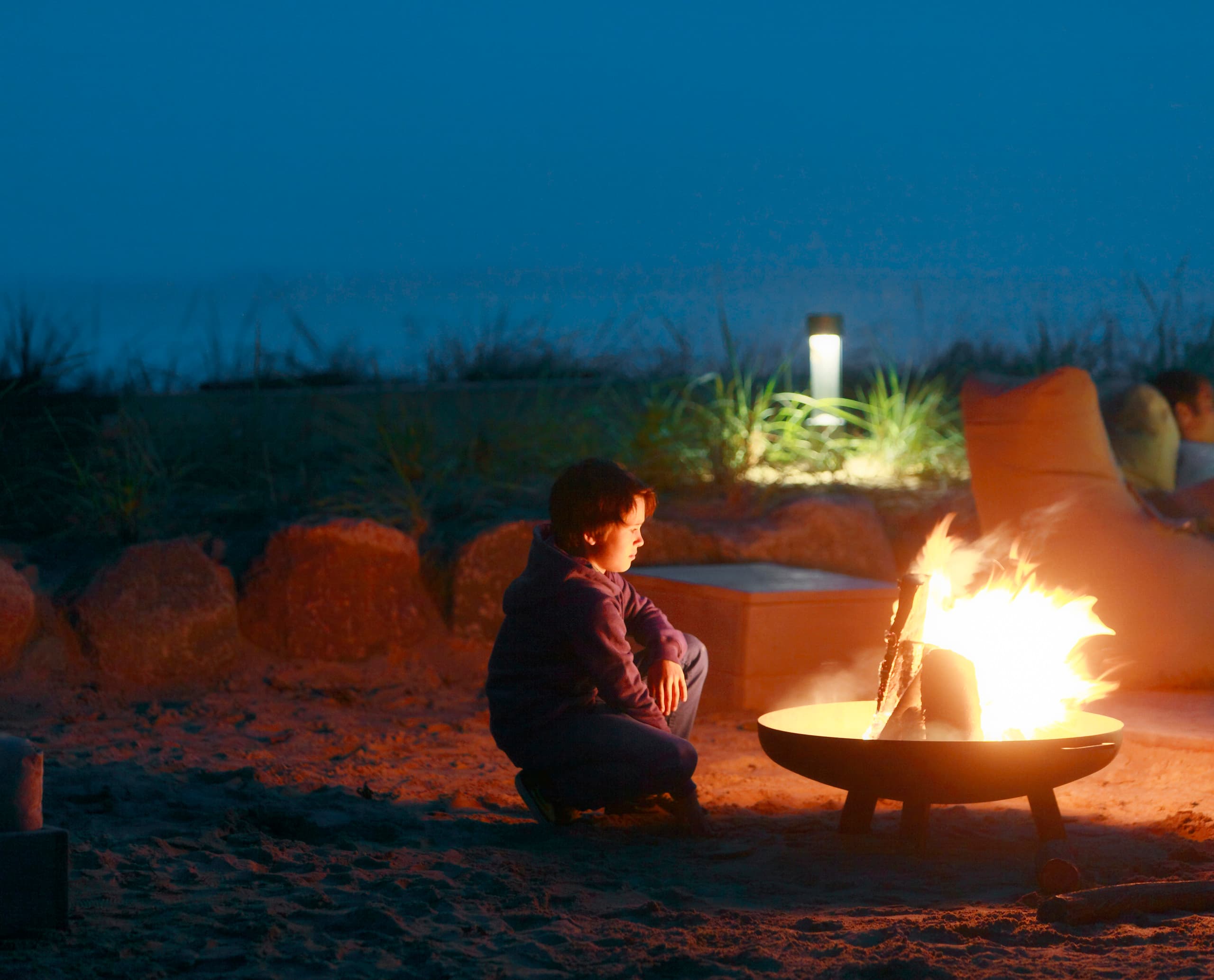 Feuerstelle mit ERCO Außenleuchten im Weissenhaus Grand Village Resort & Spa. Gemütliche Atmosphäre mit moderner Beleuchtung.