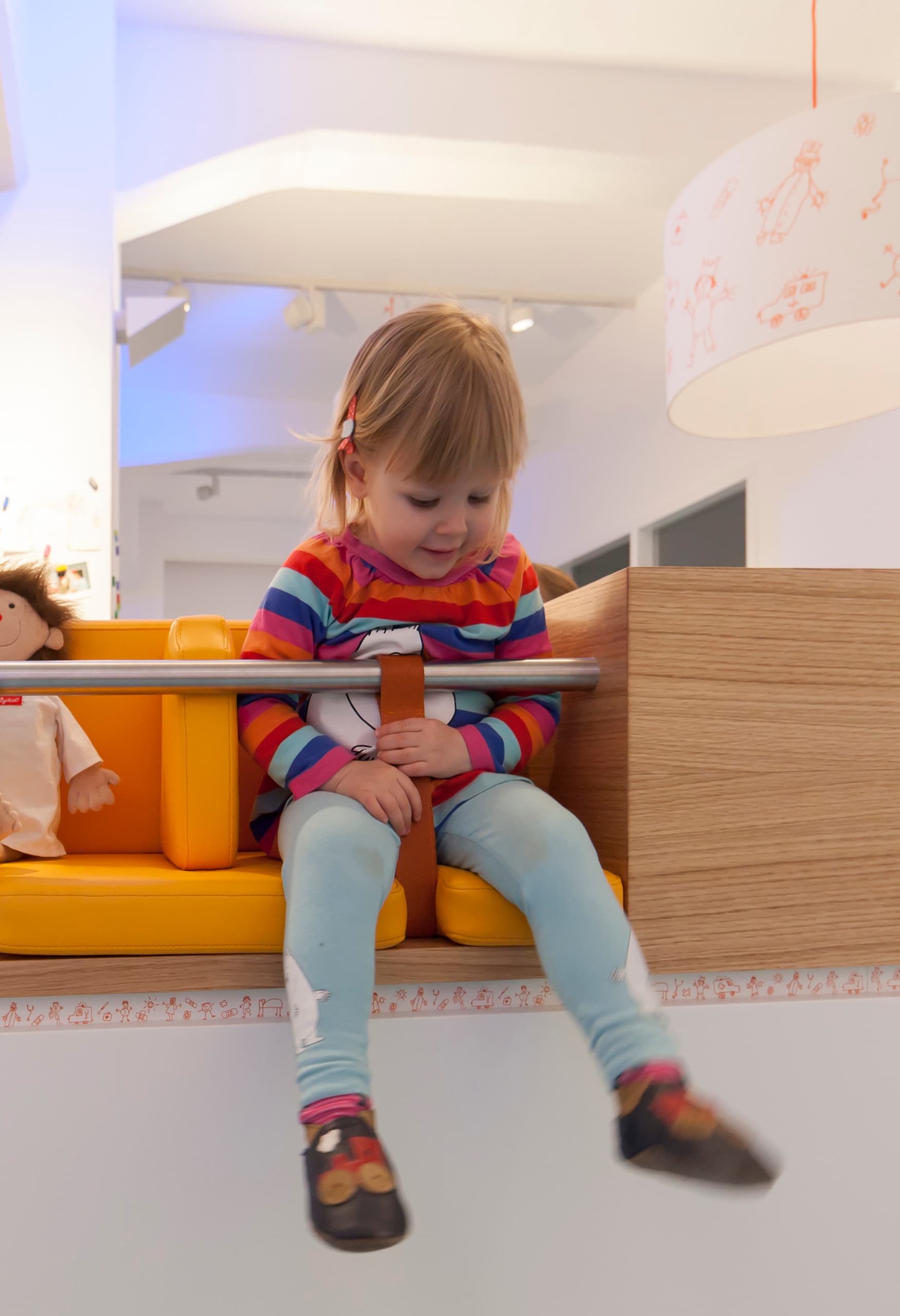 Kind wartet im freundlichen Wartebereich der Uhlig Kinderarztpraxis, beleuchtet mit ERCO LED-Leuchten.