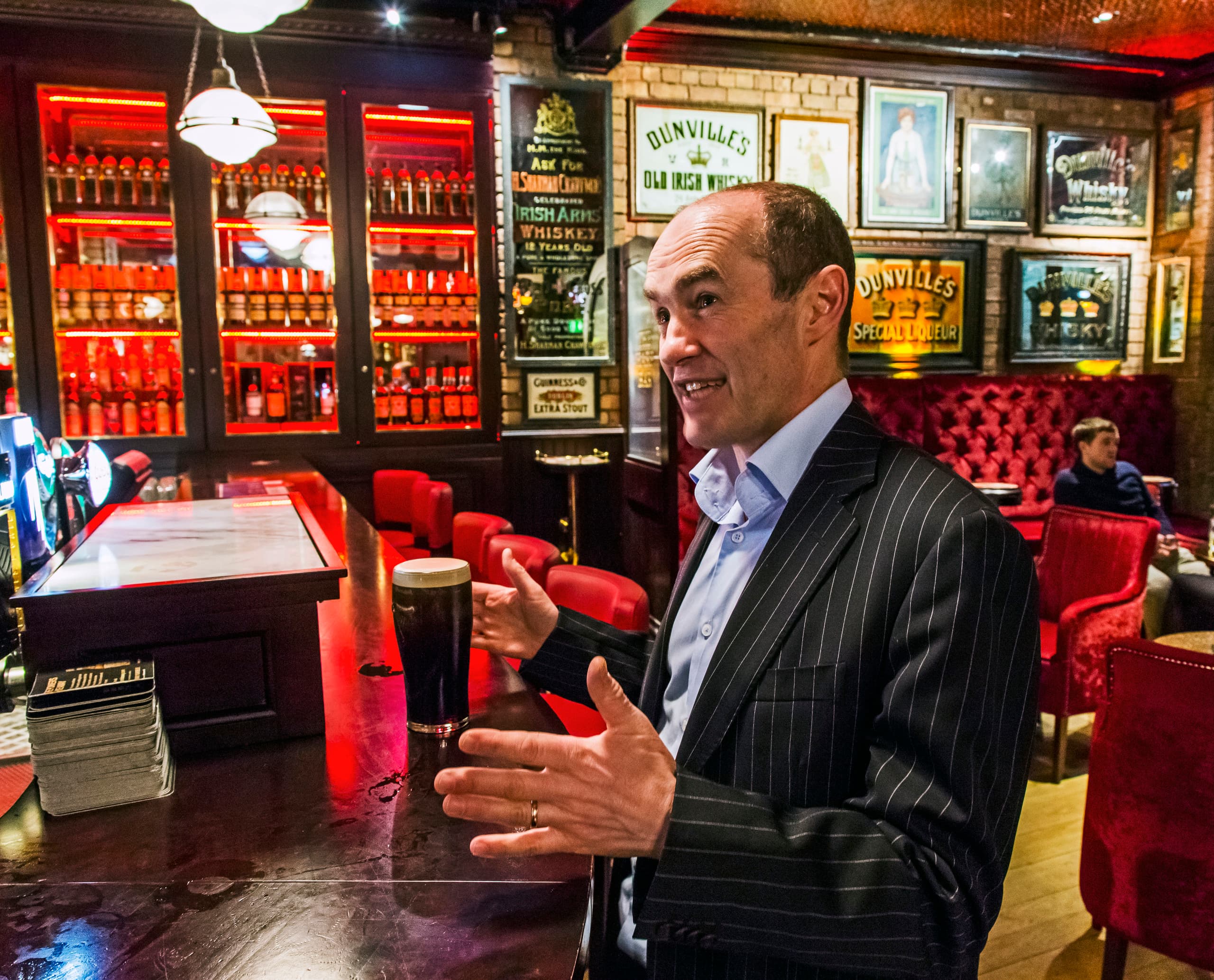 Mann im Harp Bar, Belfast, mit einem Guinness. LED-Beleuchtung akzentuiert die viktorianische Einrichtung.