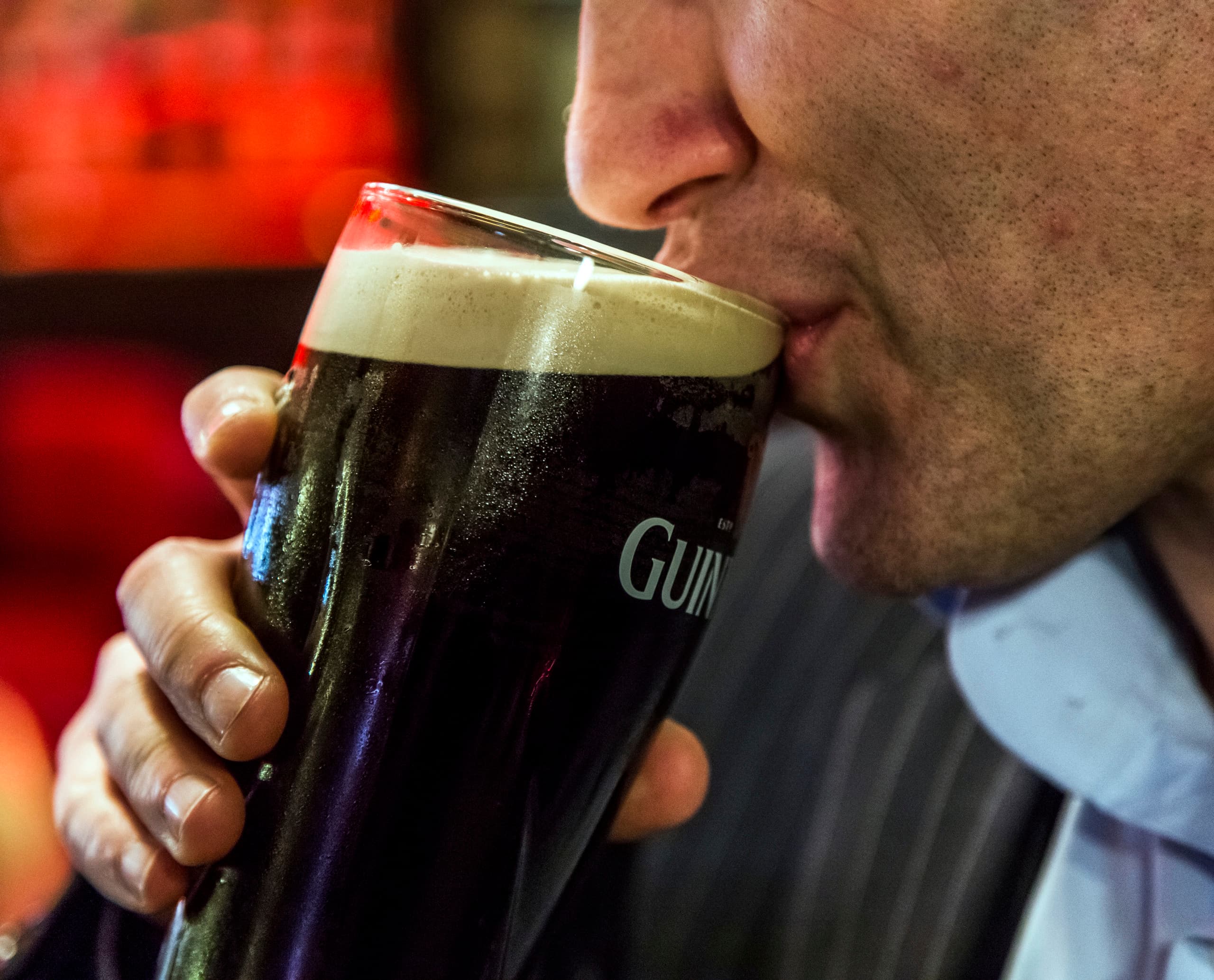 Ein Mann trinkt ein Guinness Stout in der Harp Bar, Belfast.
