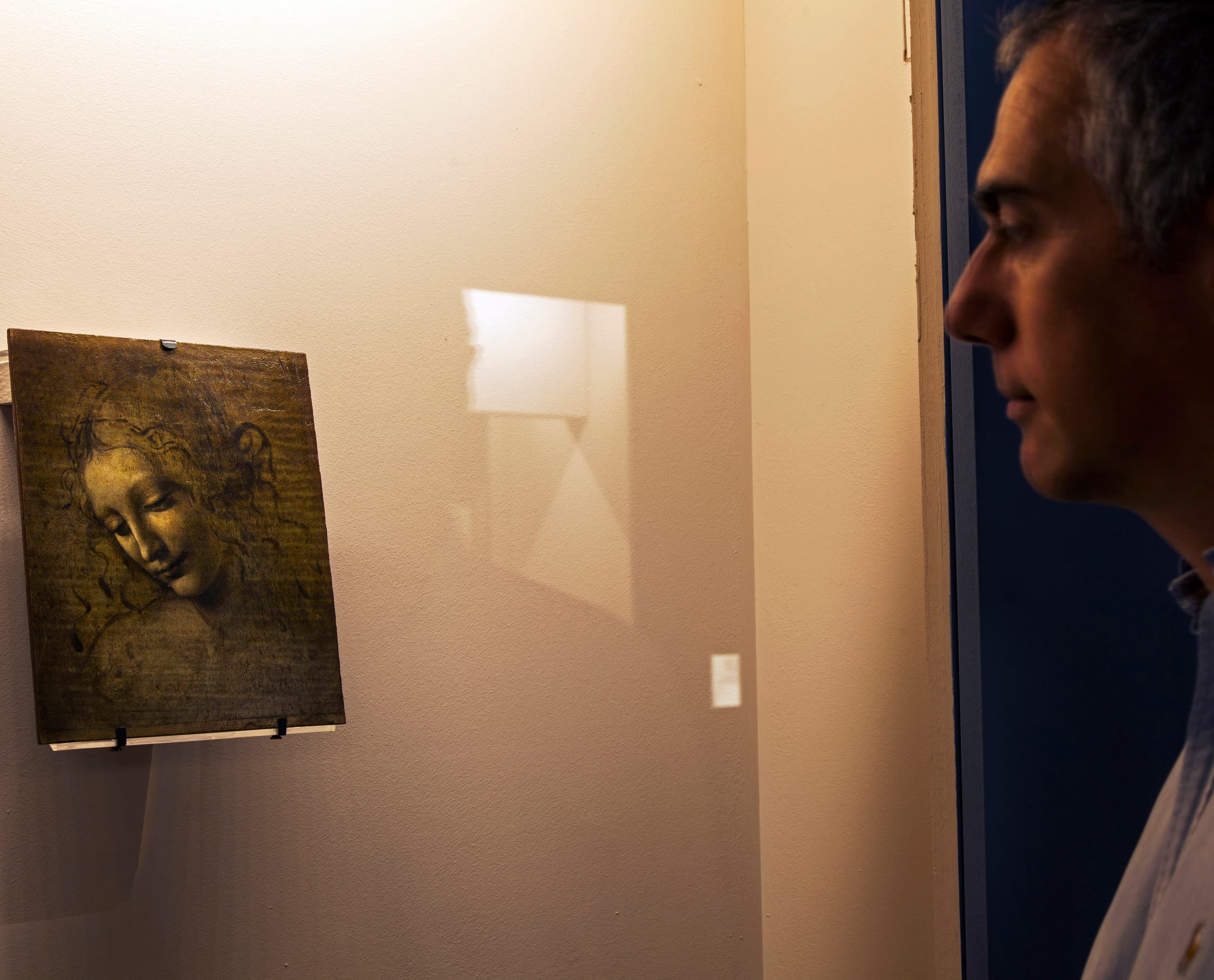 Ein Besucher betrachtet ein Gemälde von Leonardo da Vinci, beleuchtet mit ERCO LED-Strahlern, in einer Ausstellung.