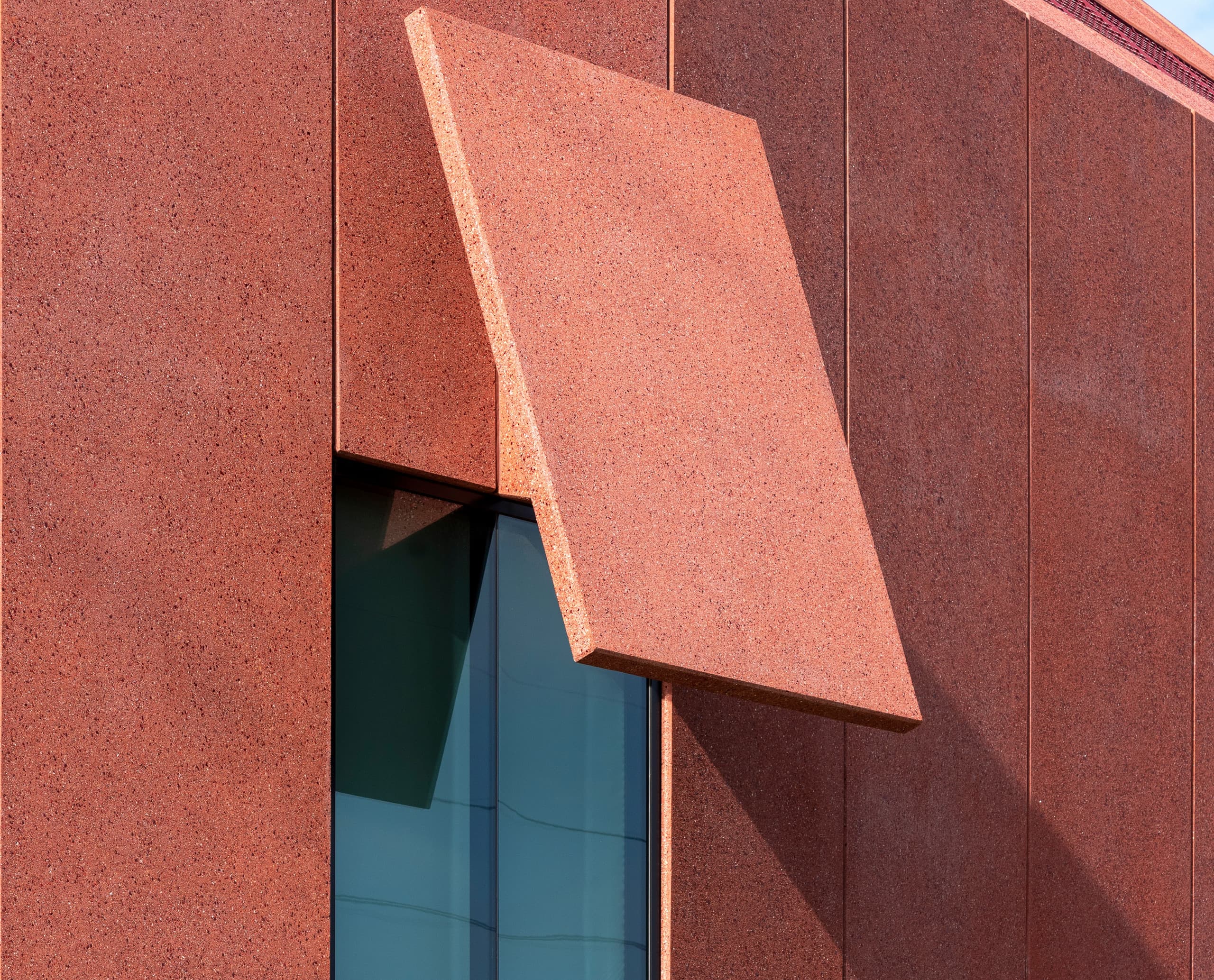Detailansicht der Fassade des Ruby City Museums mit roter Betonverkleidung und Fenster