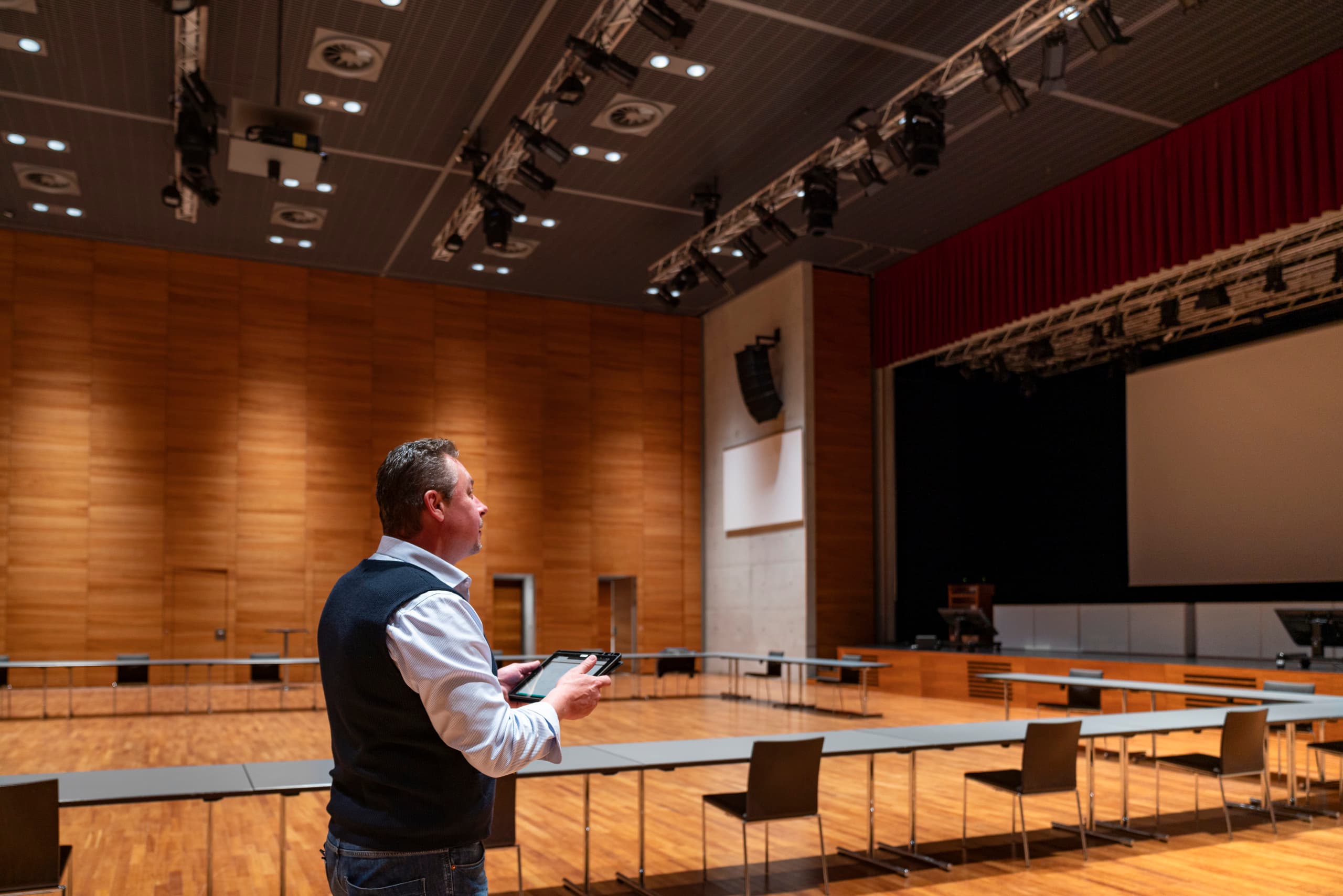Mann mit Tablet im Ferry Porsche Congress Center, Zell am See. ERCO LED-Beleuchtung für Energieeffizienz.