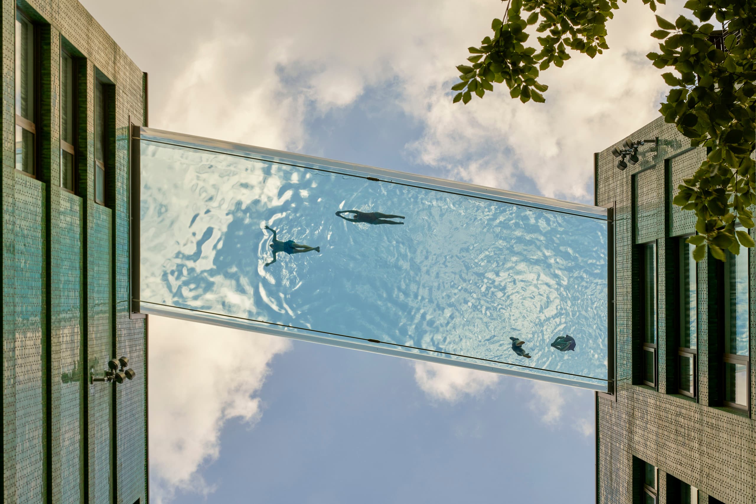 Sky Pool Embassy Gardens in London: Schwimmende Menschen in luftiger Höhe, beleuchtet mit ERCO Kona Strahlern.