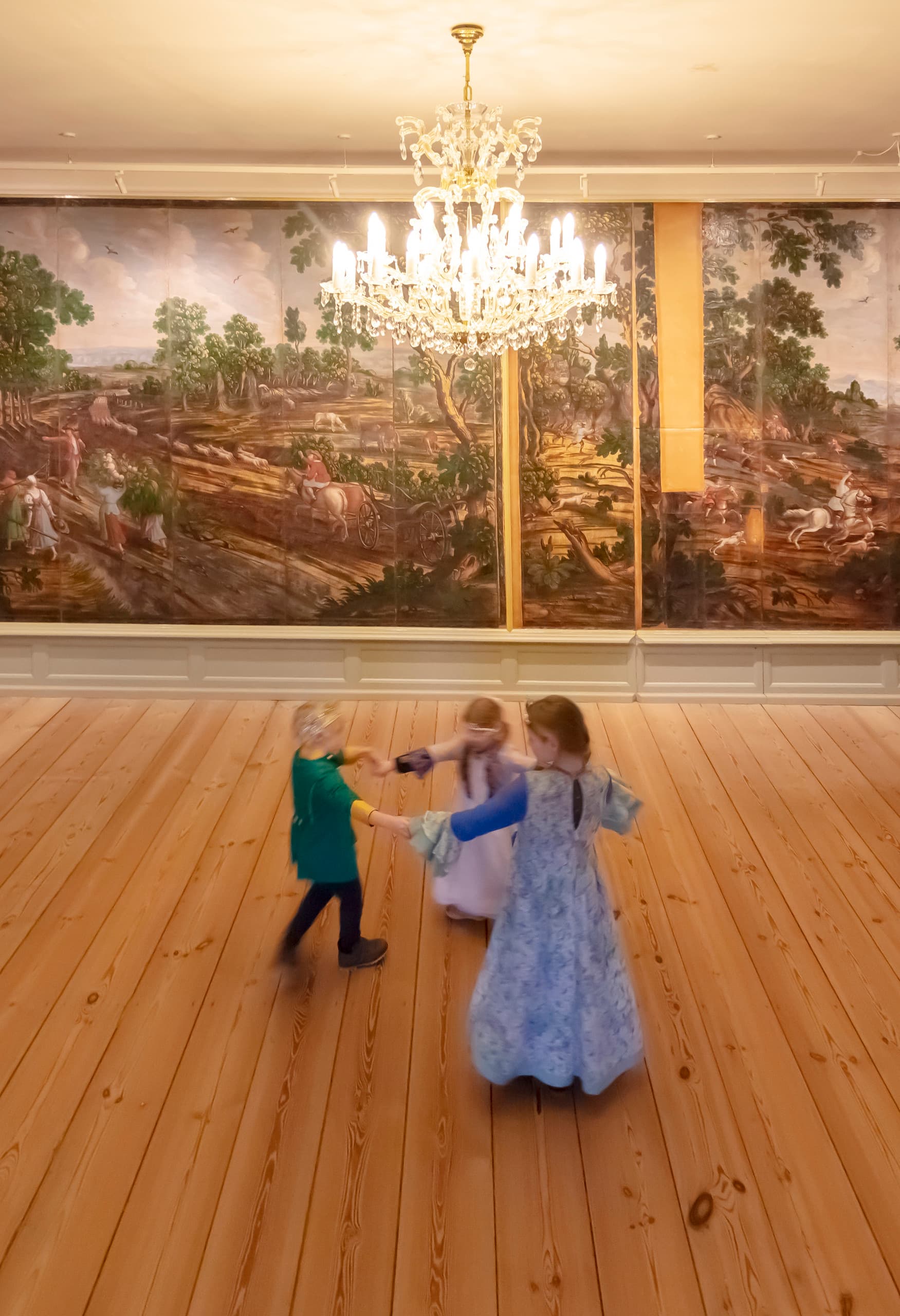 Glücksburg Schloss Interieur mit Eclipse Strahlern, die historische Wandteppiche beleuchten, während Kinder spielen.