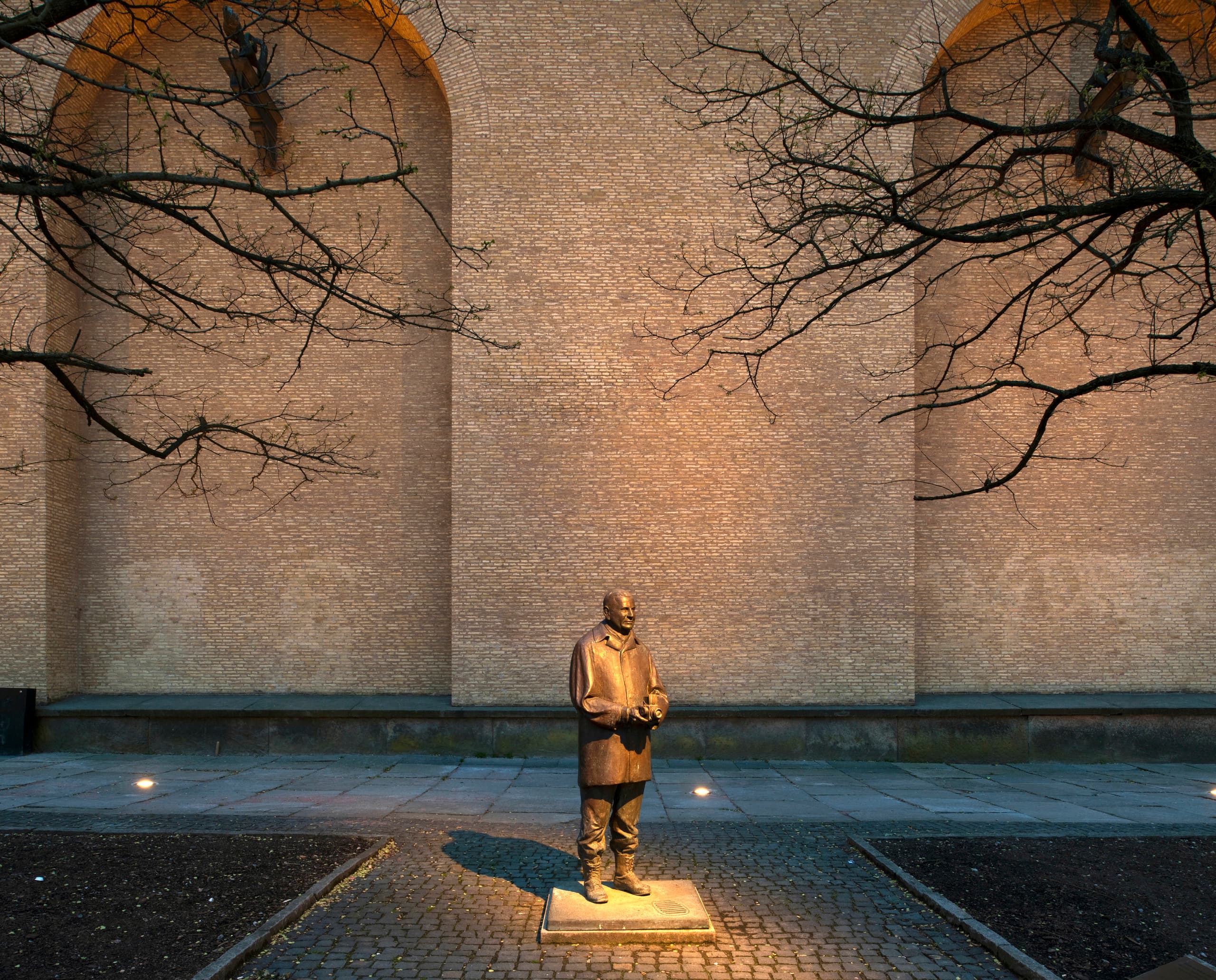 Beleuchtete Statue vor Backsteinmauer, Museumsaußenbereich mit ERCO Außenleuchten.
