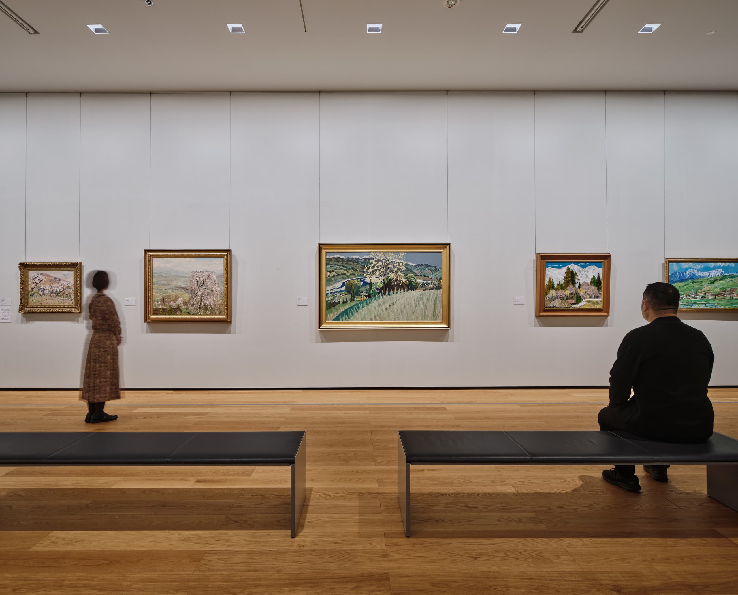 Menschen schauen sich Gemälde im Museum an.