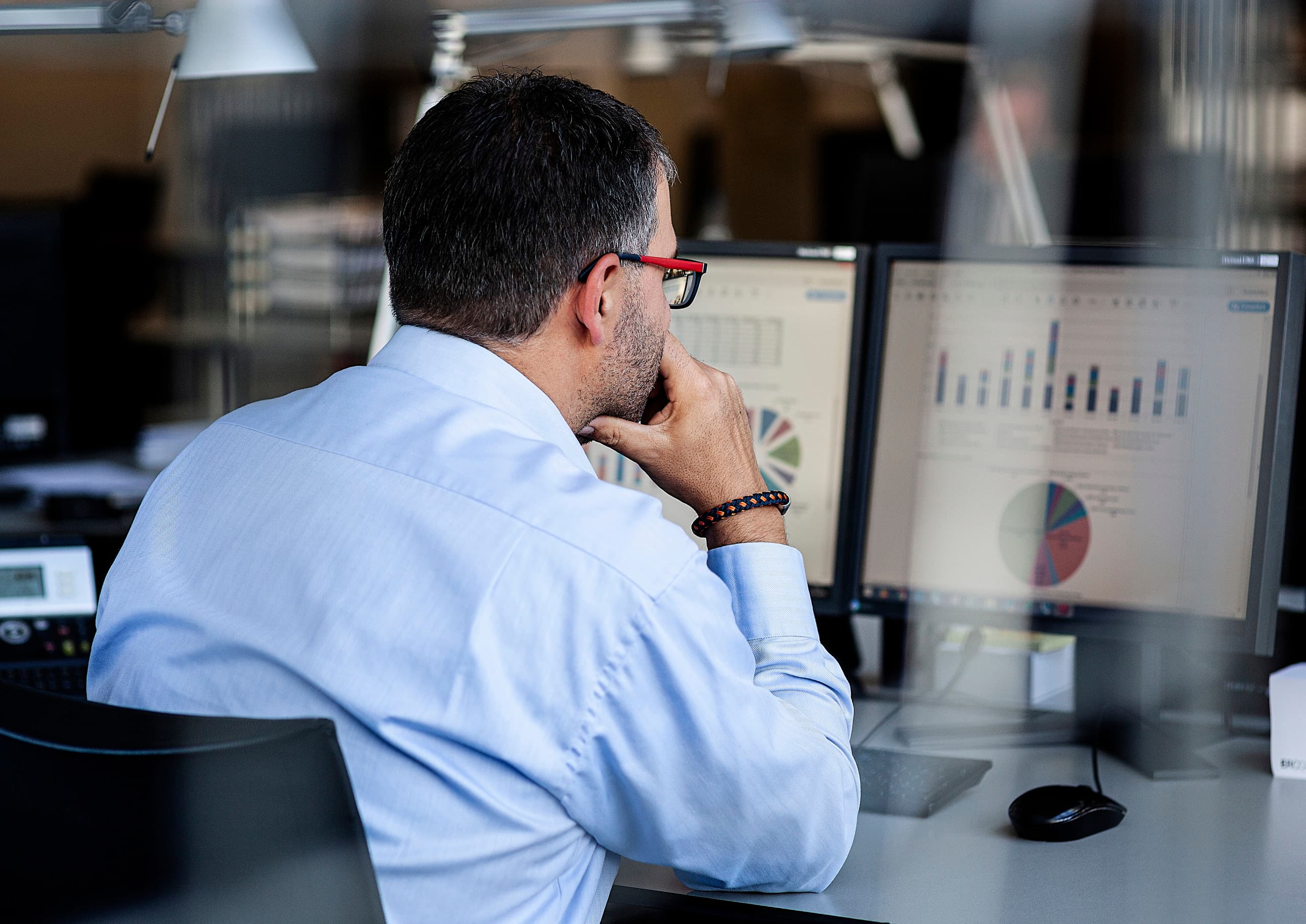 Ein Mann analysiert Daten auf zwei Monitoren im Büro.