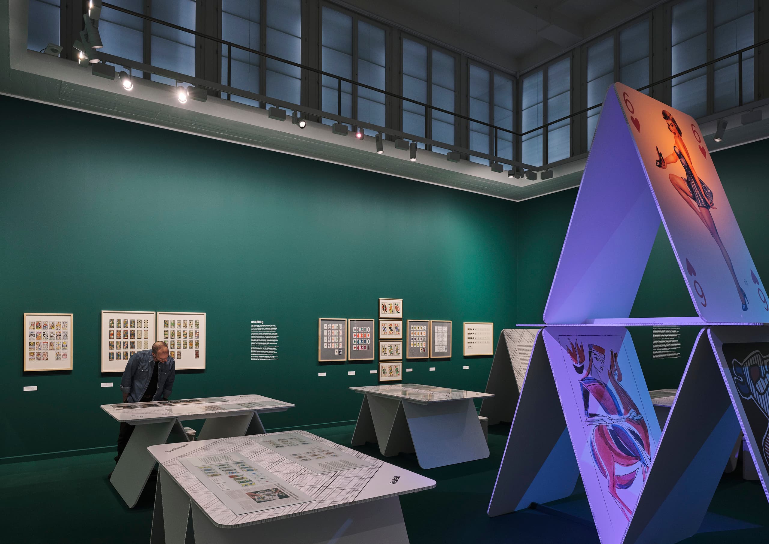Ausstellungsraum mit grüner Wand und Kartendeck-Kunstintallation.