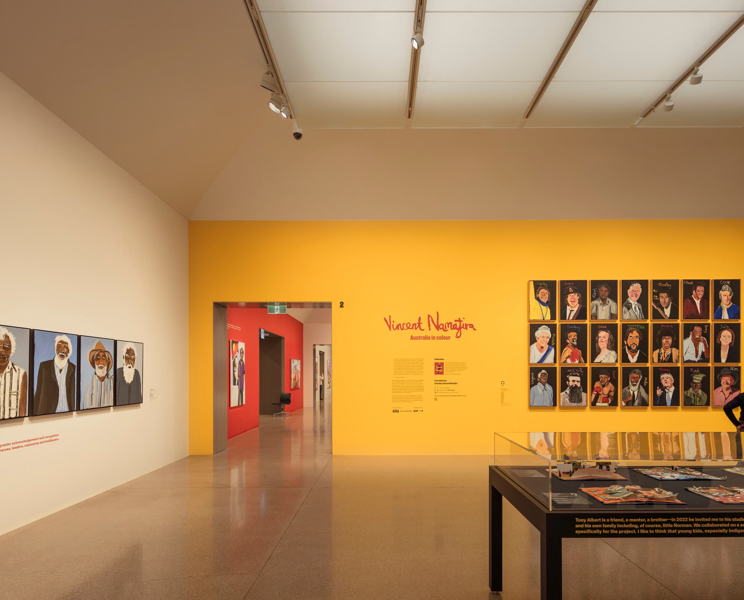 Gelbe und weiße Wand in Ausstellungsraum mit Bildern.