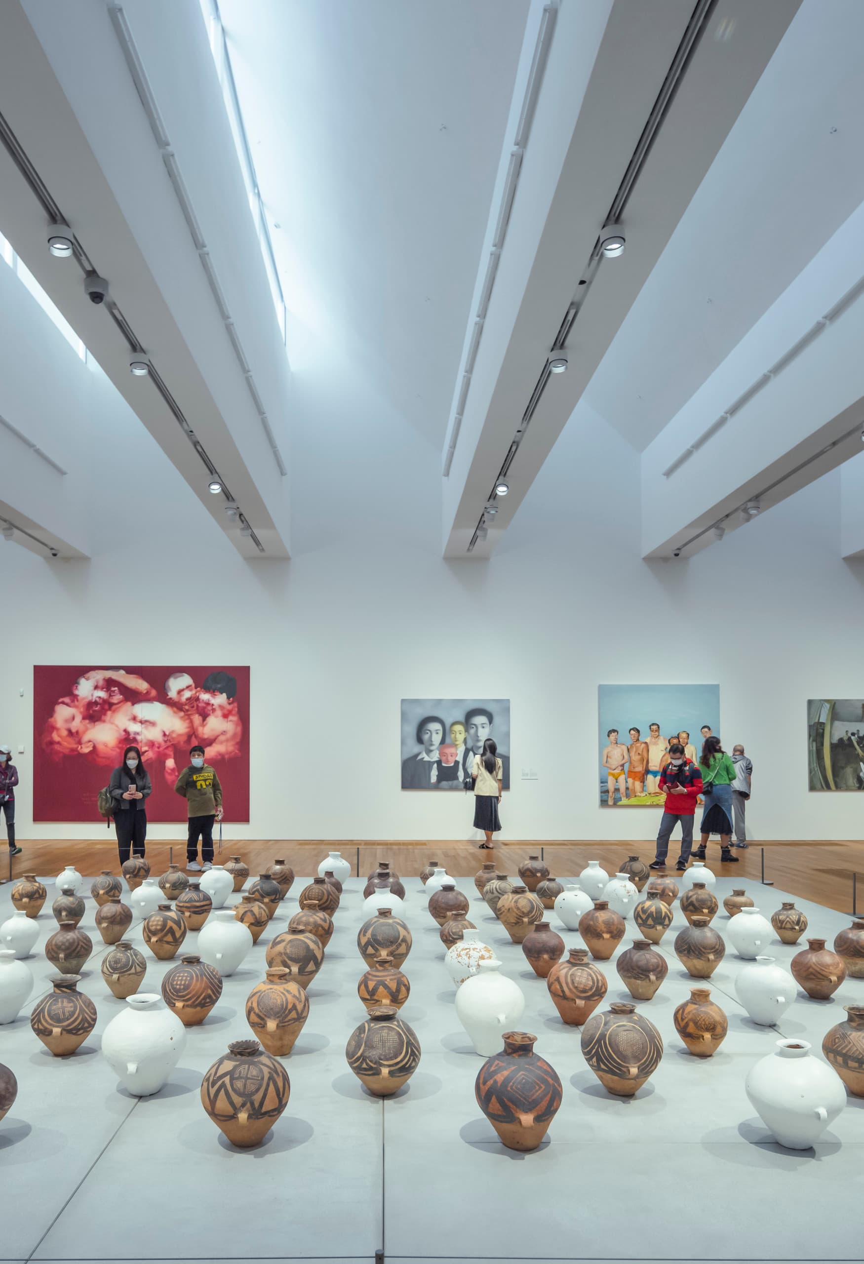Besucher betrachten Kunstwerke im M+ Museum, beleuchtet mit ERCO Strahlern auf Schienen.