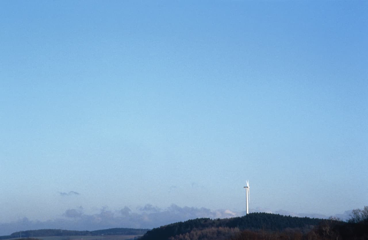 Windrad unter blauem Himmel, Symbol für Tageslicht und Energie.