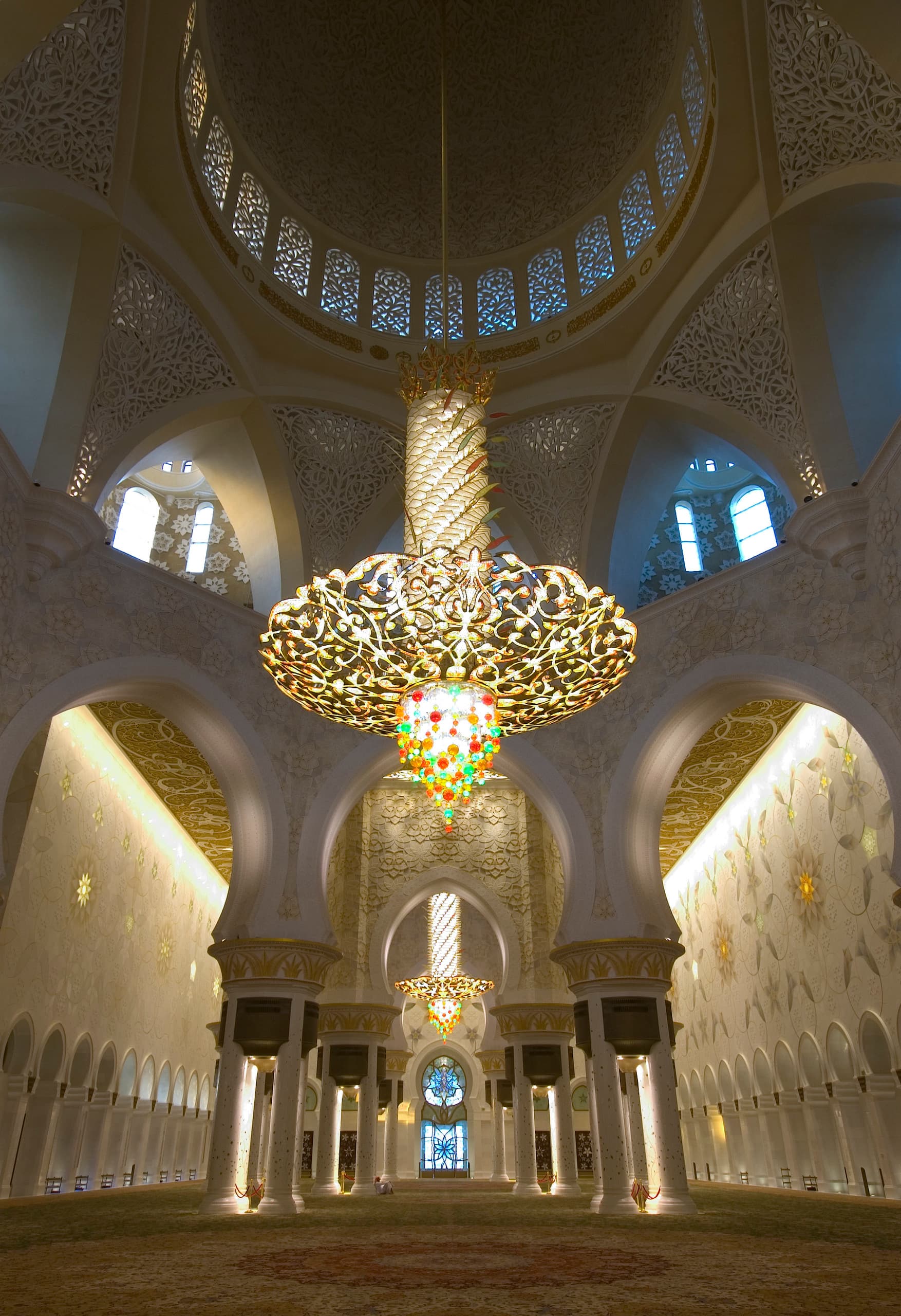 Innenansicht der Sheikh Zayed Moschee mit dekorativer Beleuchtung und kunstvollen Bögen.