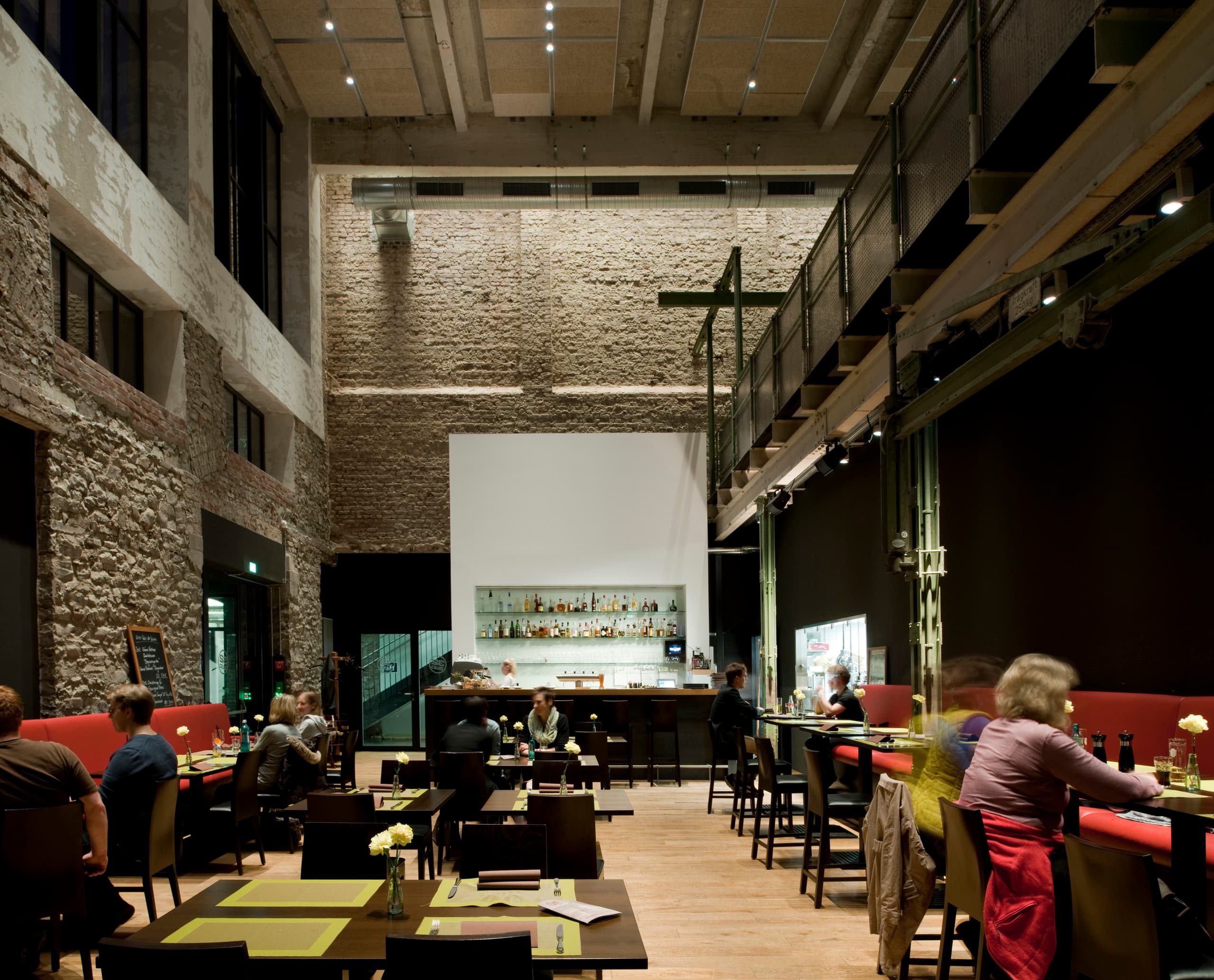 Innenansicht des Restaurants Halle 32 in Gummersbach mit ERCO Optec Strahlern, die die industrielle Architektur hervorheben.
