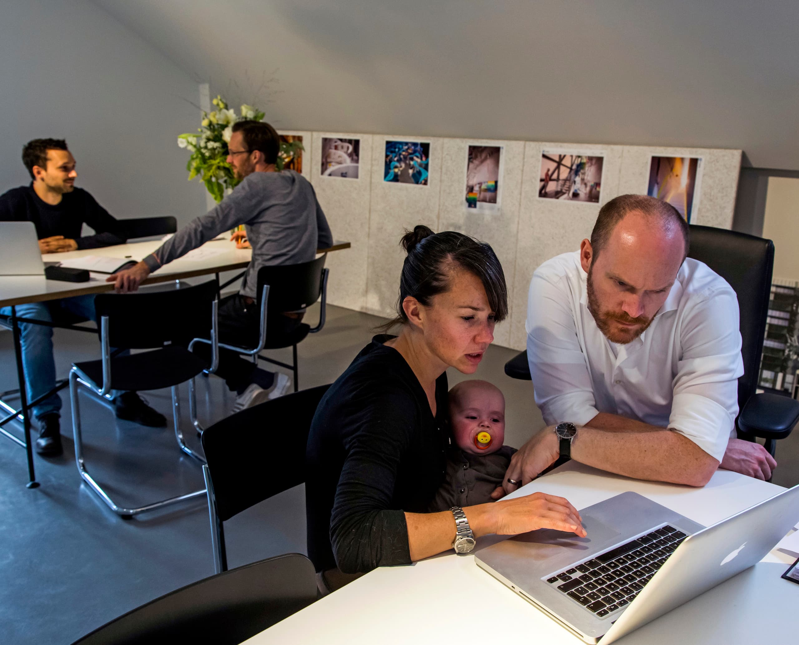 Archimedes Agentur Büro: Team arbeitet mit Laptop, inklusive Baby, unter ERCO Bürobeleuchtung.