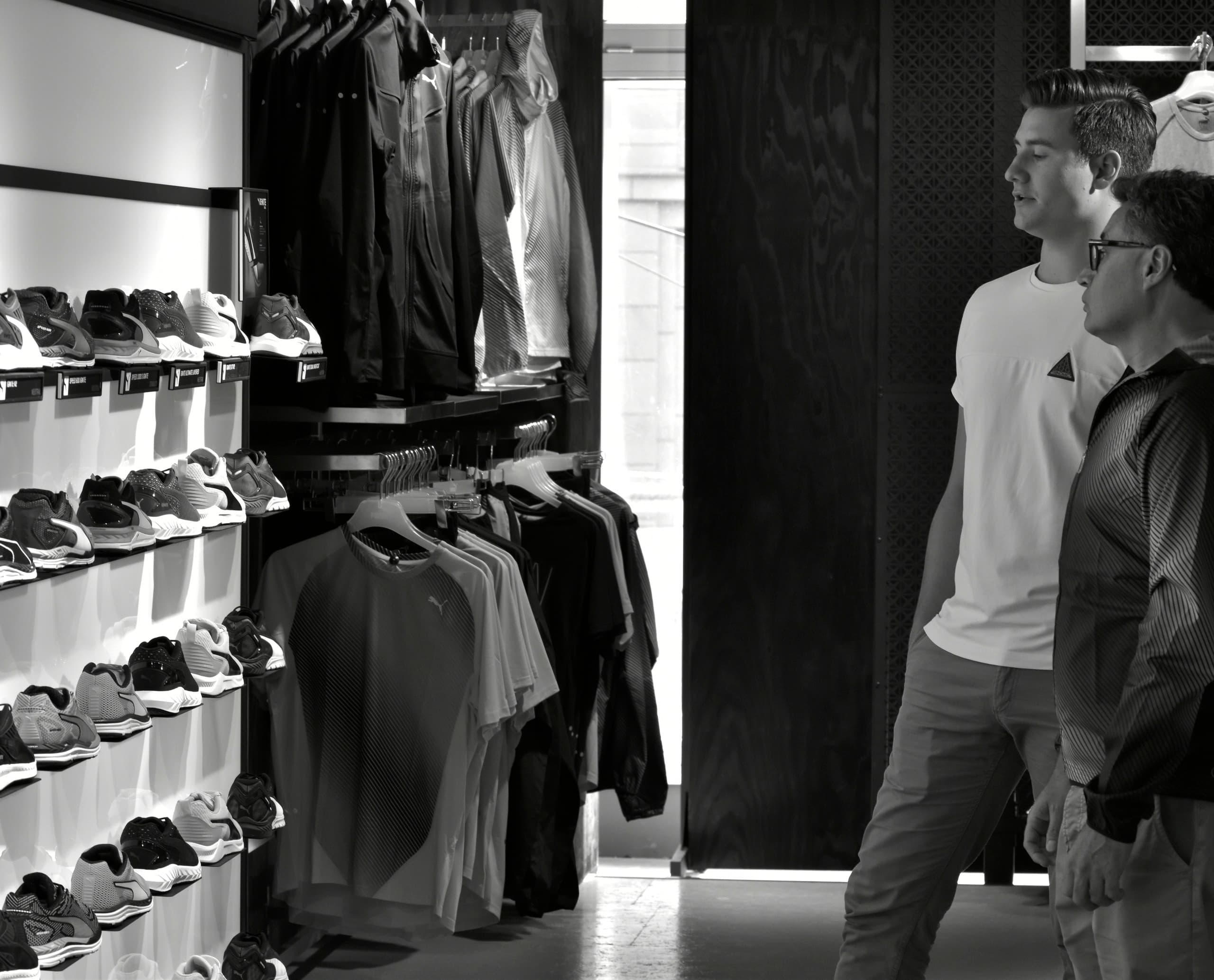 Kunden im PUMA Store Berlin, beleuchtet mit ERCO Optec Strahlern, die Waren und Bereiche hervorheben.