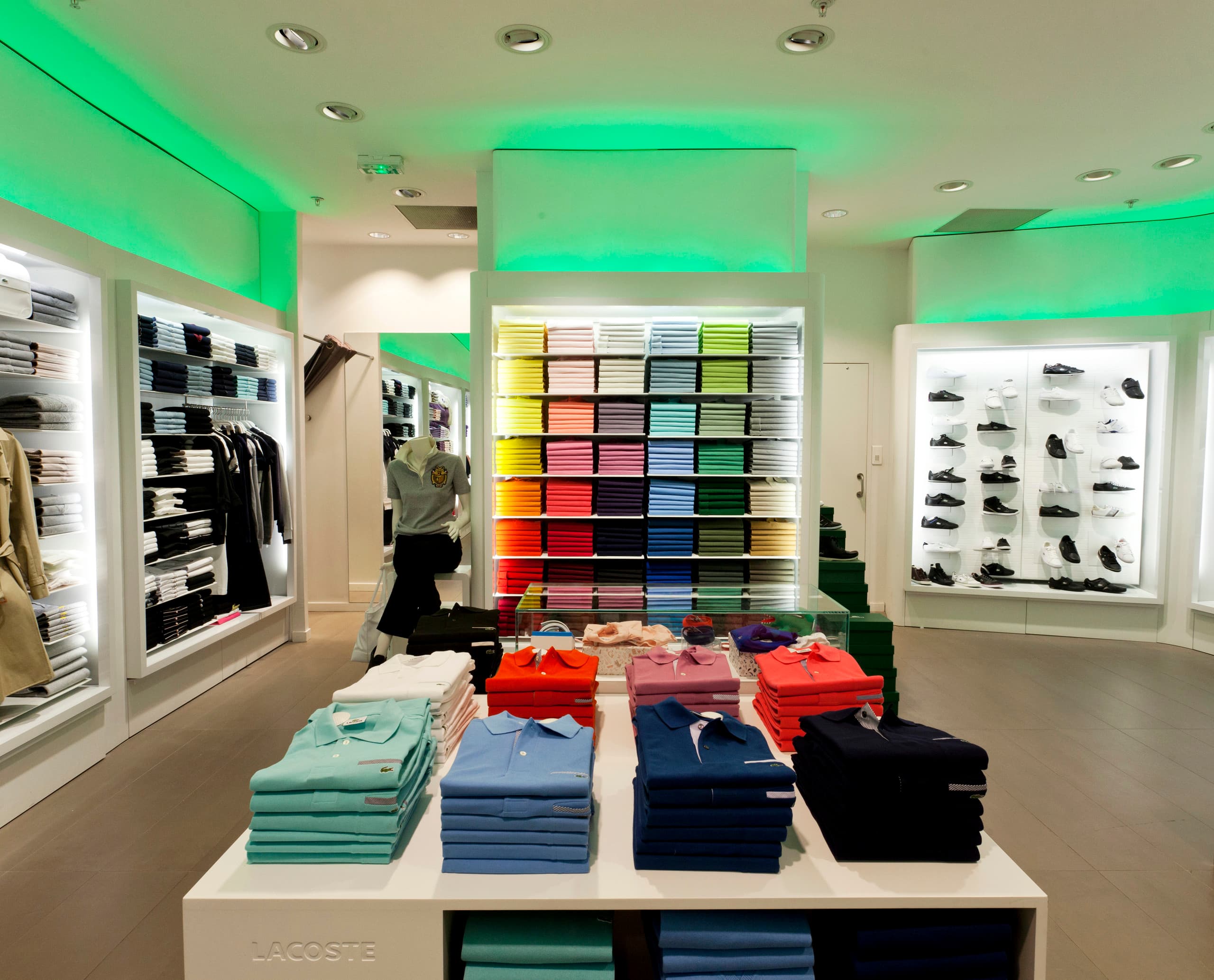 Lacoste-Store mit farbiger Bekleidung unter Akzentbeleuchtung.