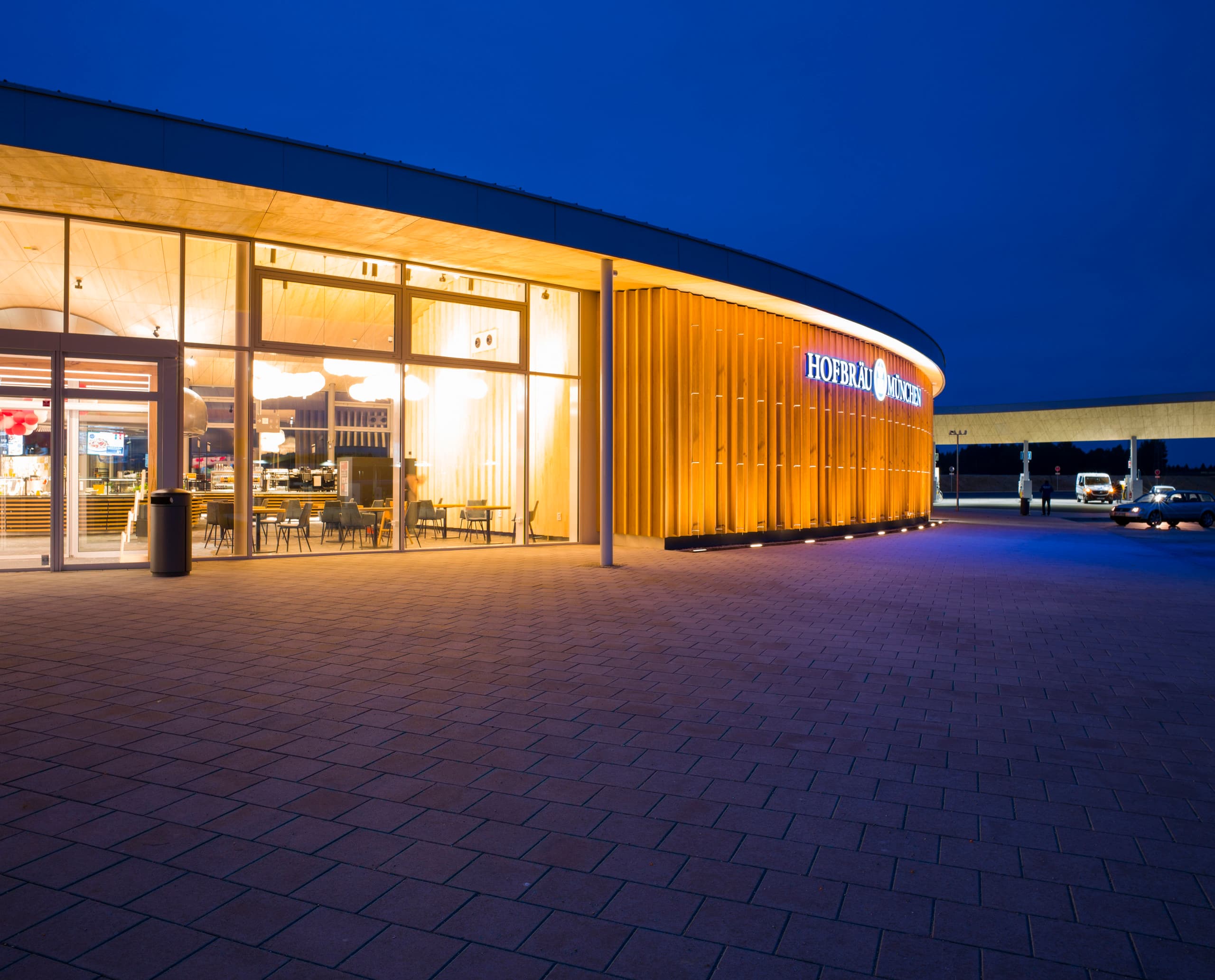 Beleuchtete Fürholzen Tankstelle an der A9 mit einladendem Shop und Restaurant, entworfen mit ERCO Licht.