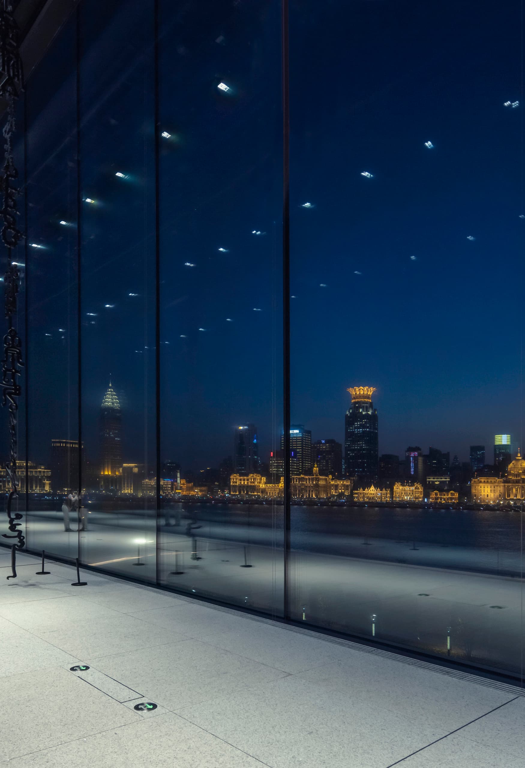 Museum of Art Pudong, Shanghai, mit ERCO LED-Beleuchtung und Blick auf die Skyline bei Nacht.