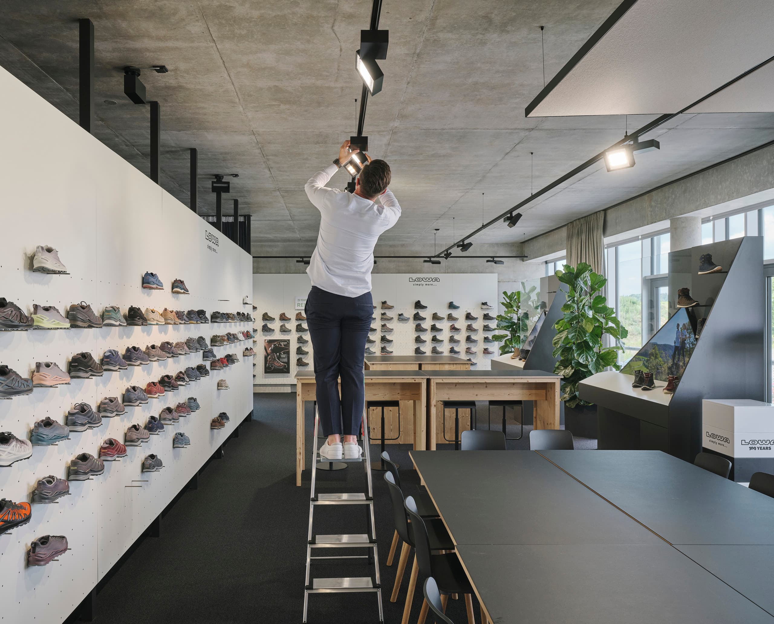Ein Mann justiert ERCO Strahler im Lowa Büro, optimiert die Beleuchtung für die Schuhpräsentation.