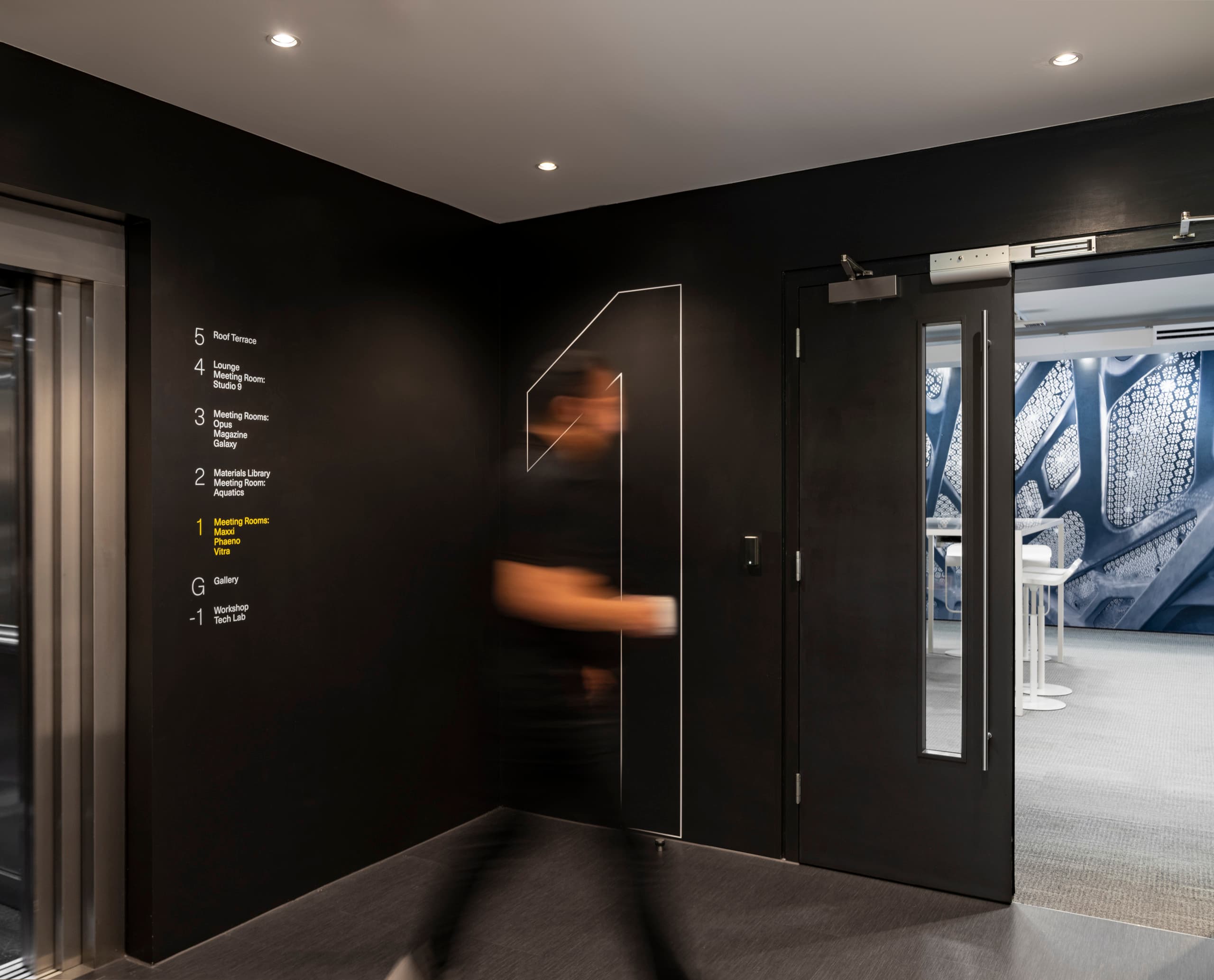 ERCO Lichtdesign in Zaha Hadid Büro London: Flur mit Wegweiser zu Meetingräumen und Aufzug.