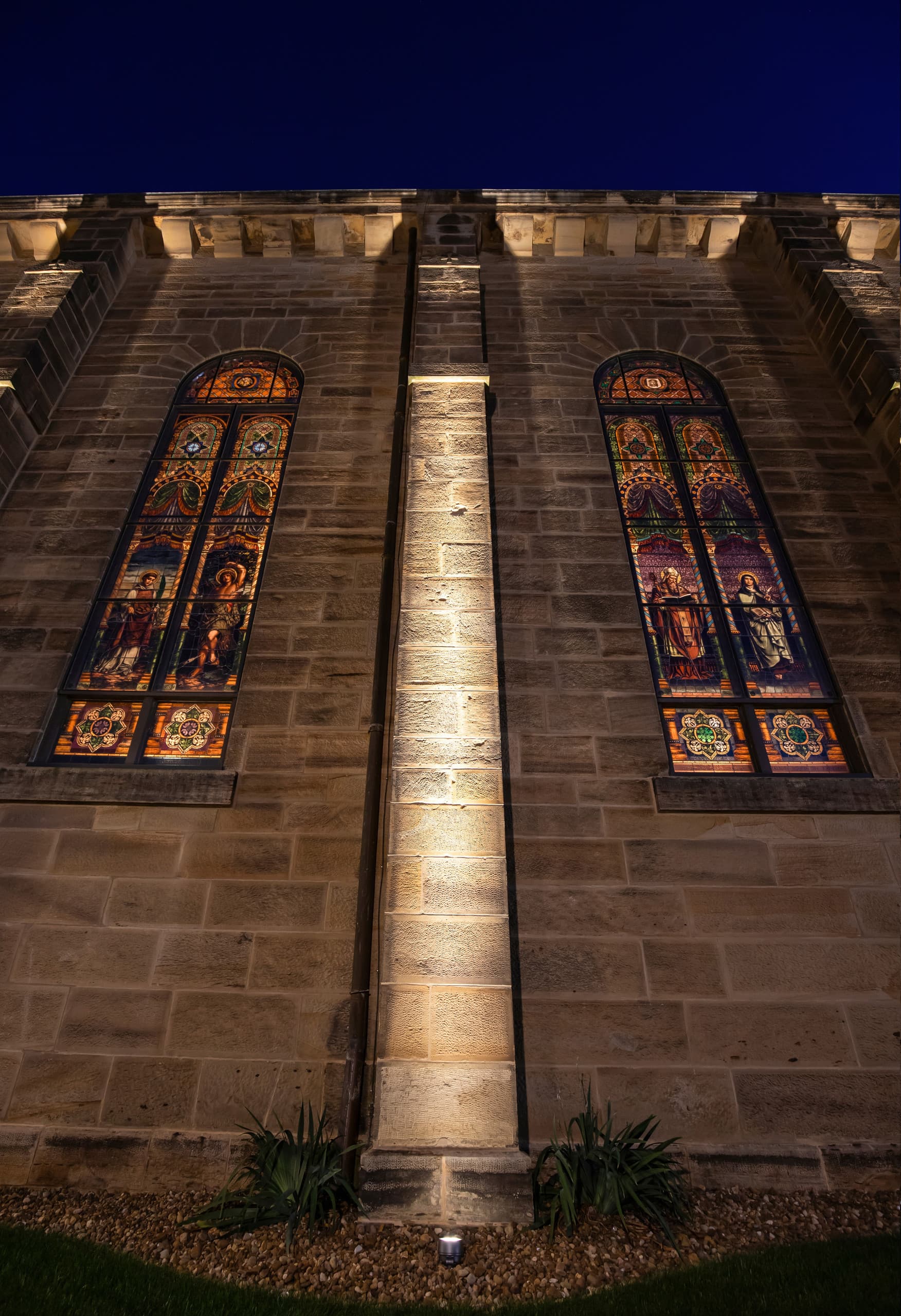St. Joseph Kirche Fassade mit ERCO Kona Projektoren beleuchtet die Sandsteinfassade und Buntglasfenster.
