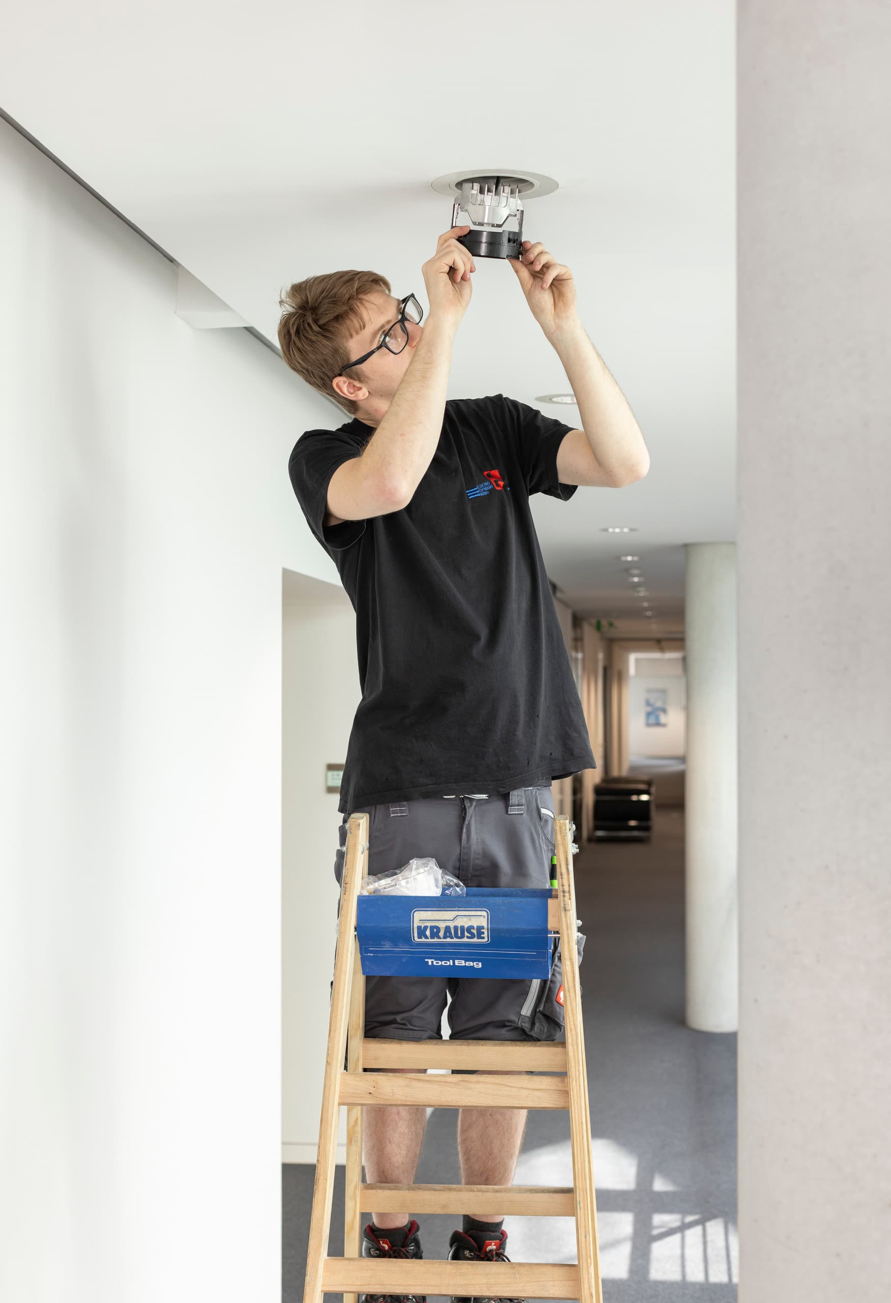 Elektriker installiert ERCO LED-Downlight in Sparkasse Ulm für verbesserte Beleuchtung.