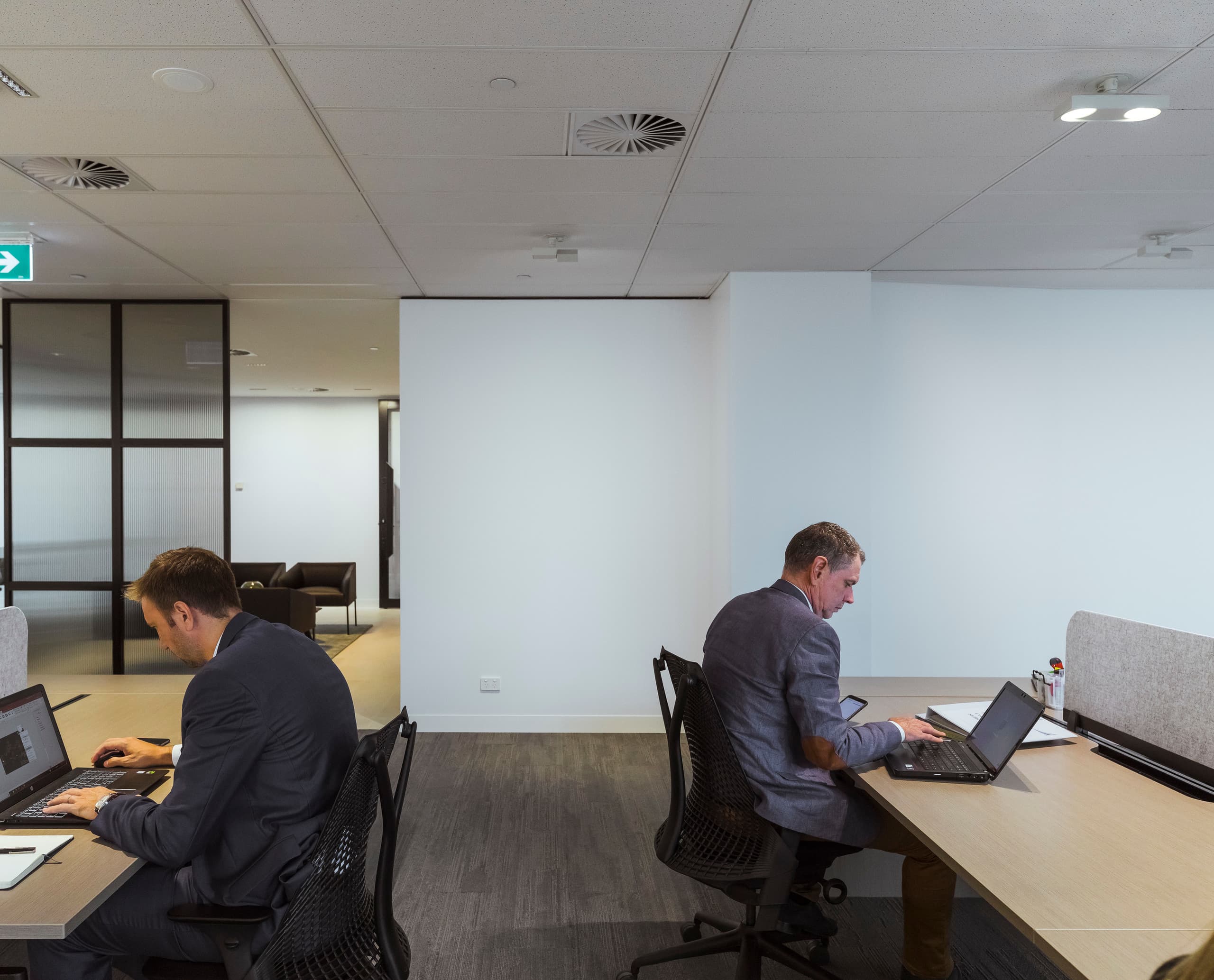 Flexible Bürobeleuchtung mit ERCO Jilly Downlights an einem Schienensystem für moderne Arbeitsplätze.