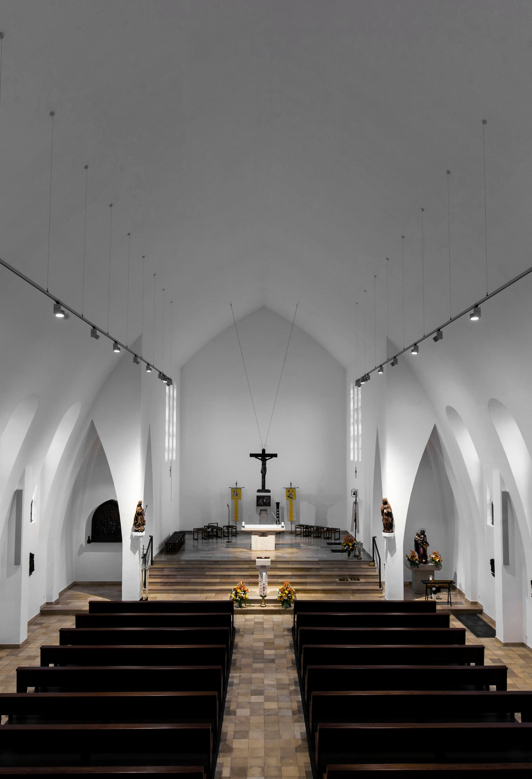 Innenansicht der St. Mariä Geburt Kirche mit ERCO Strahlern auf Schienen, die den Raum beleuchten.