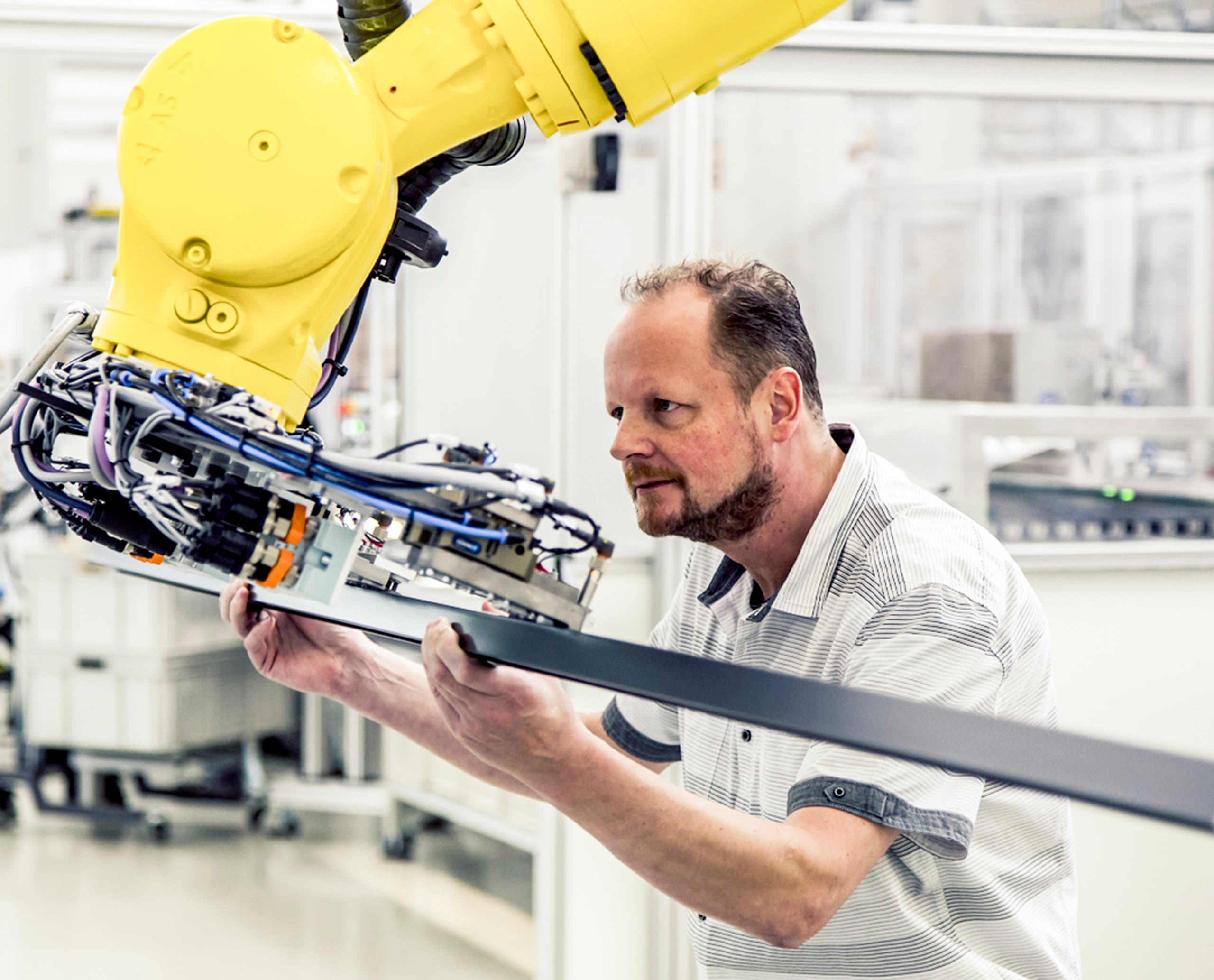 ERCO Mitarbeiter arbeitet mit einem gelben Industrieroboter an der Produktentwicklung.