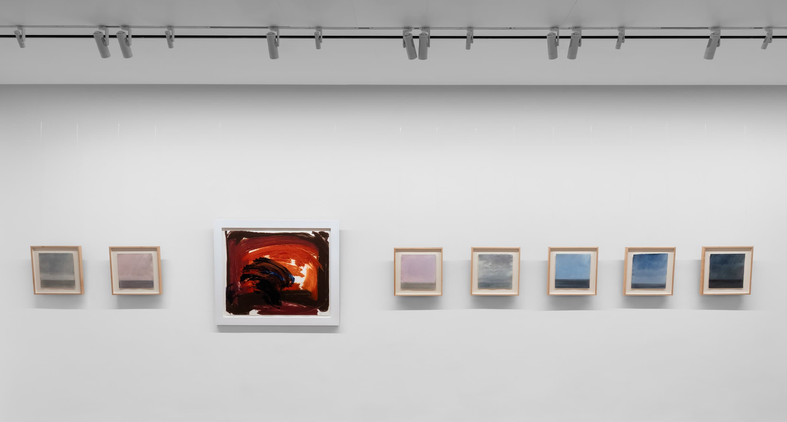 Weiße Wand mit Bildern nebeneinander, eines größer und markant rot.